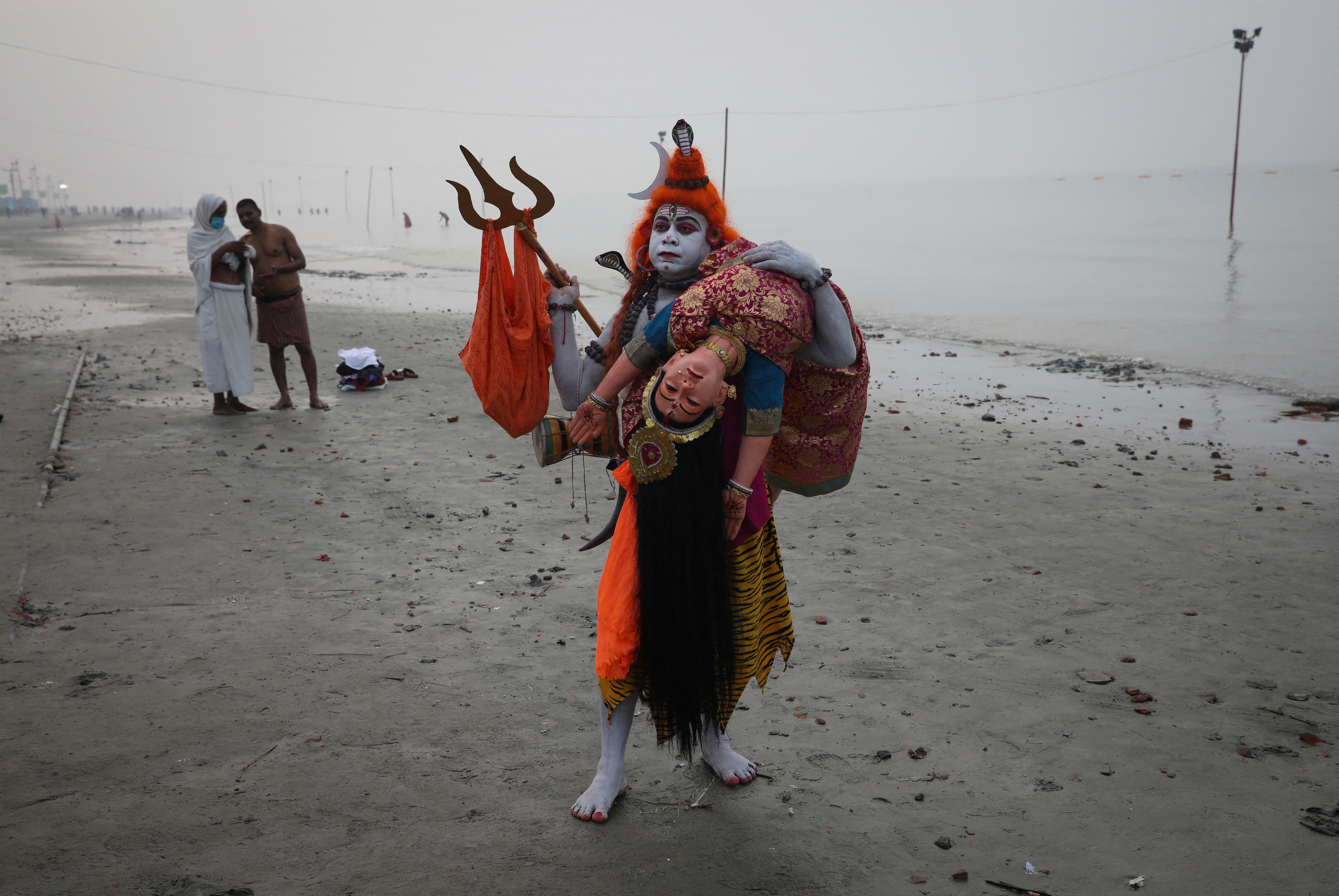 A man dressed as Hindu God, Lord Shiva, walks for alms from pilgrims at the confluence of the River Ganges and the Bay of Bengal in West Bengal