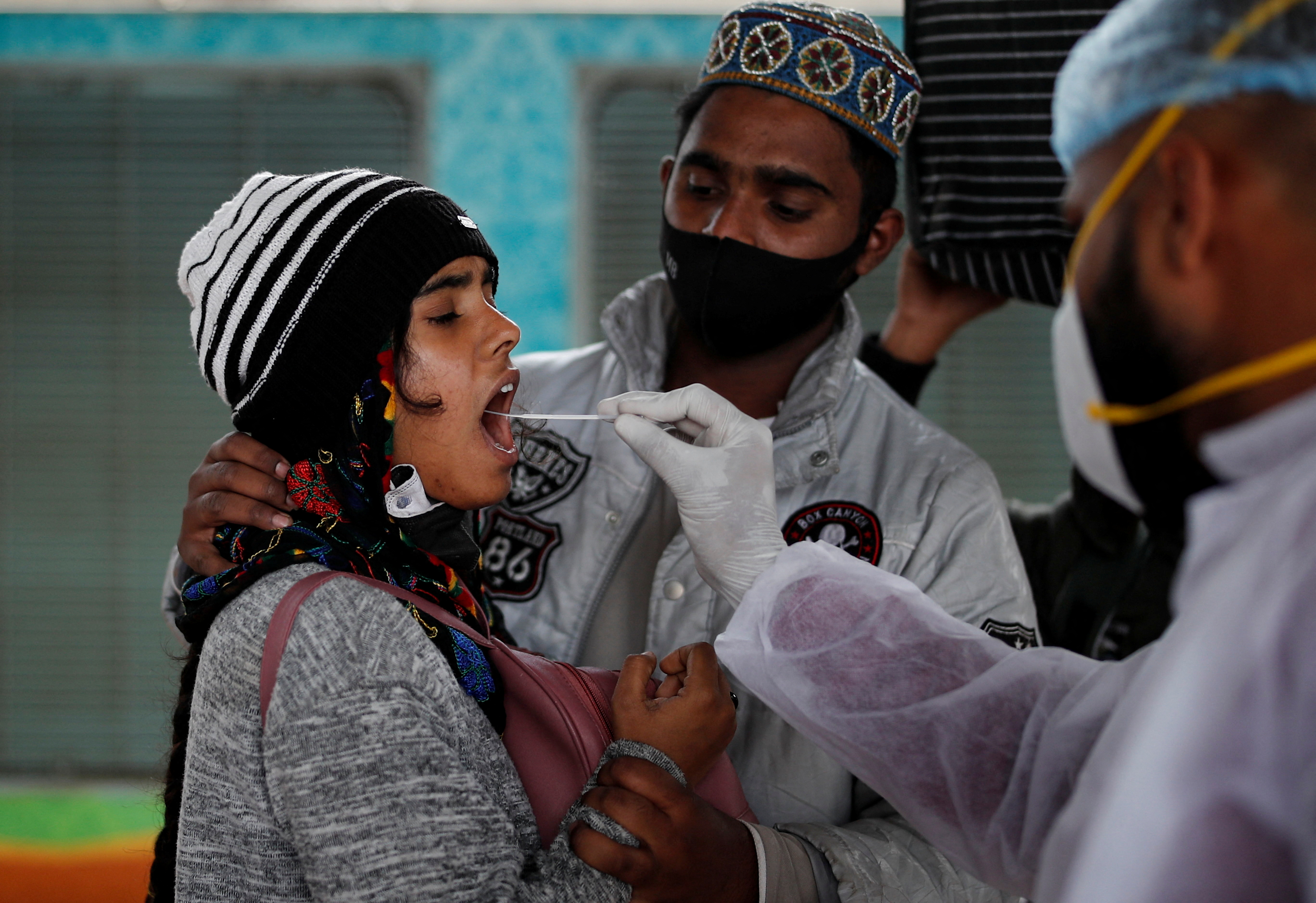 A health worker collects a swab sample from a woman during a rapid antigen testing campaign for the coronavirus disease at a railway station in Mumbai