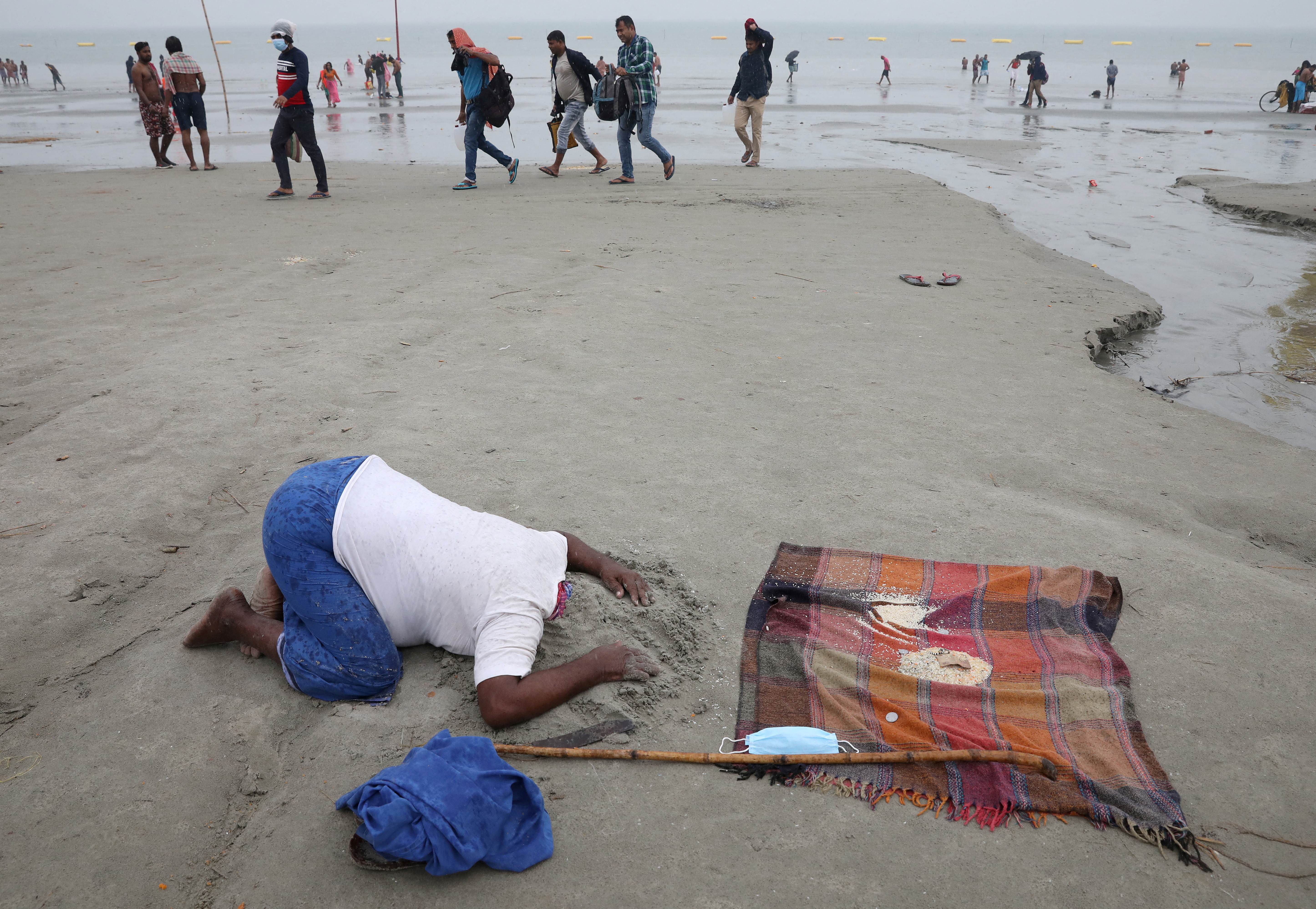 A man performs to receive alms from pilgrims at the confluence of the river Ganges and the Bay of Bengal on the occasion of Makar Sankranti festival in West Bengal