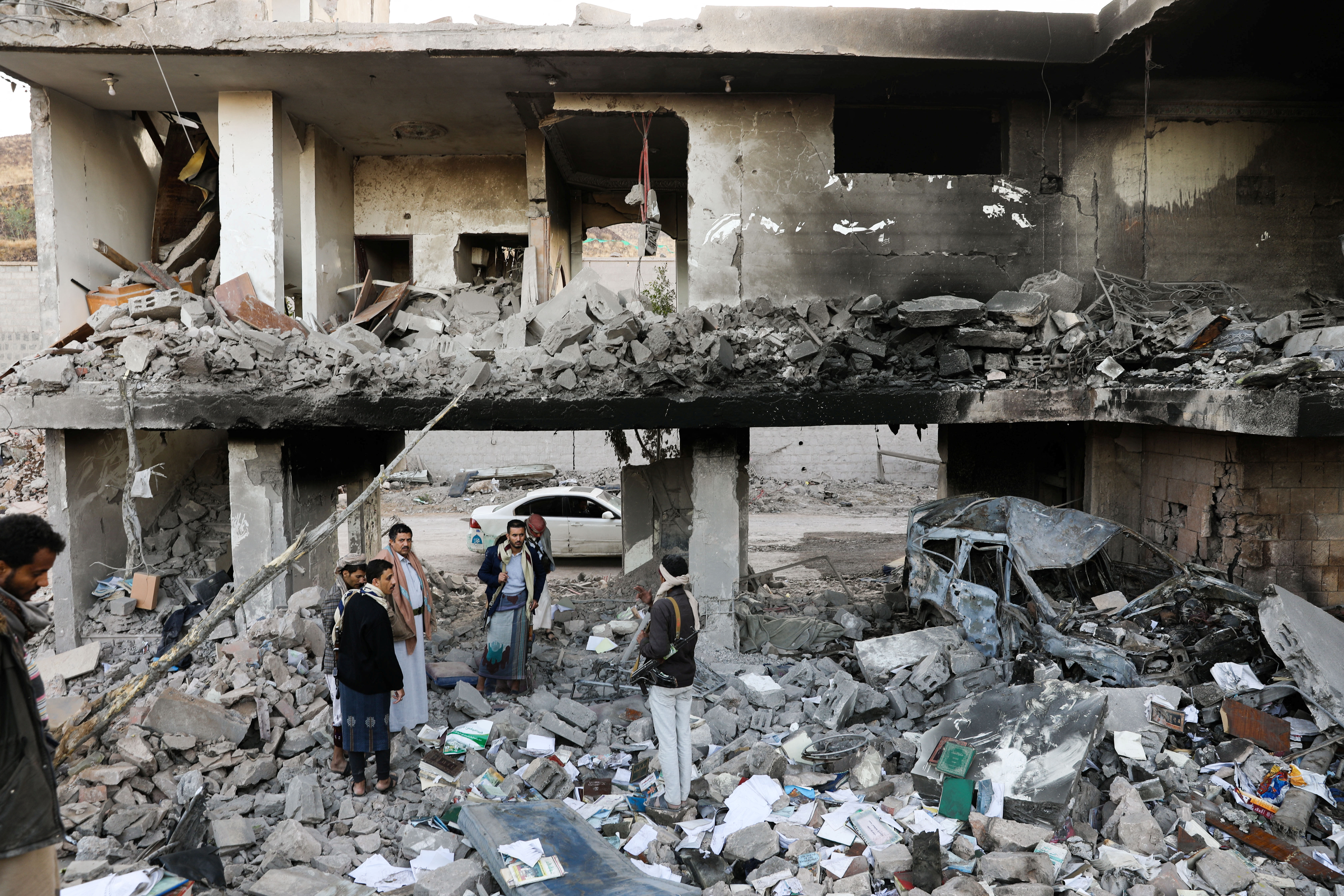 Guards stand on the rubble of a house hit by Saudi-led air raids in Sanaa, Yemen, January 18, 2022