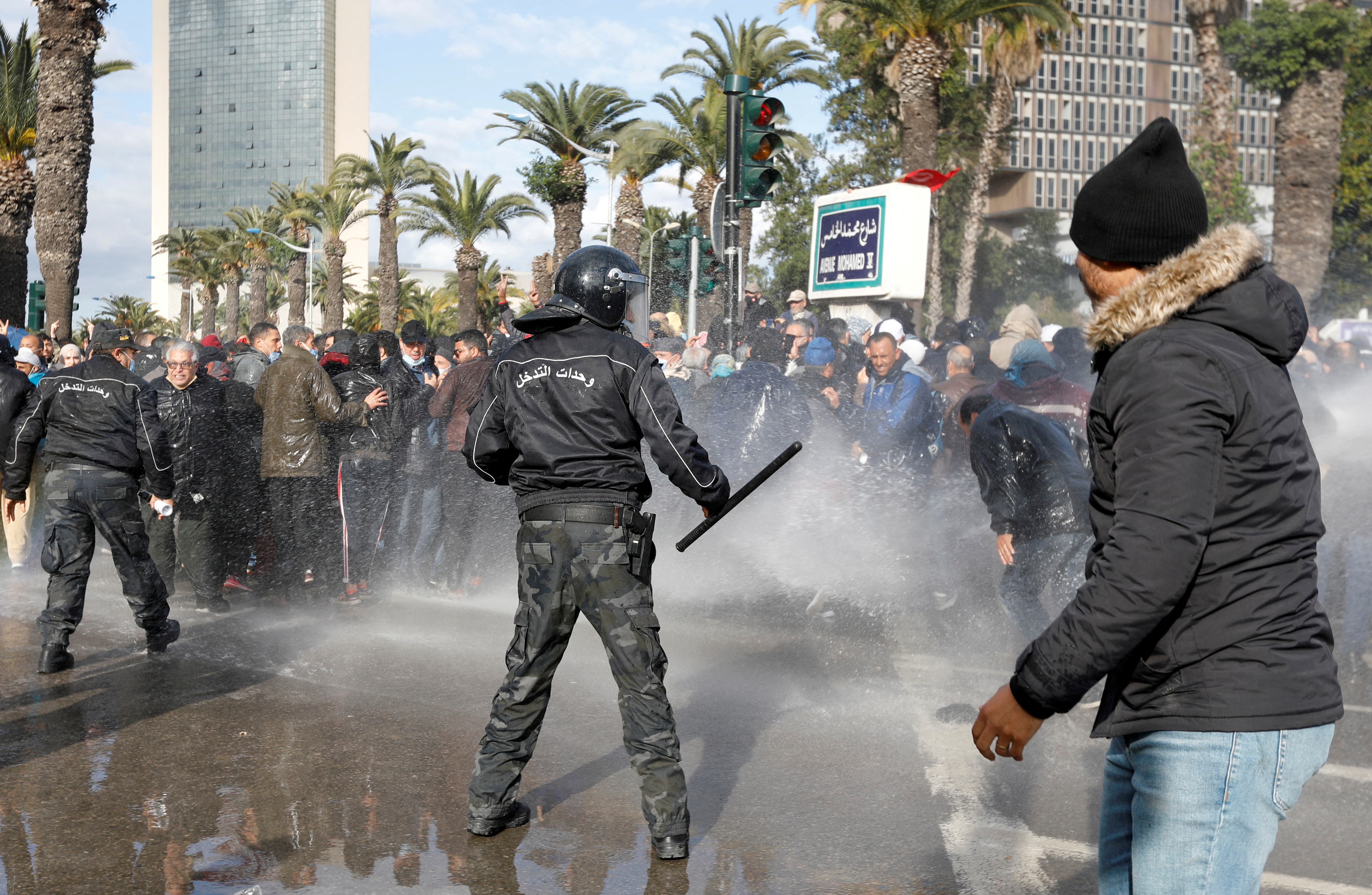 Demonstrators are hit by a water cannon during a protest against Tunisian President Kais Saied's seizure of governing powers, in Tunis