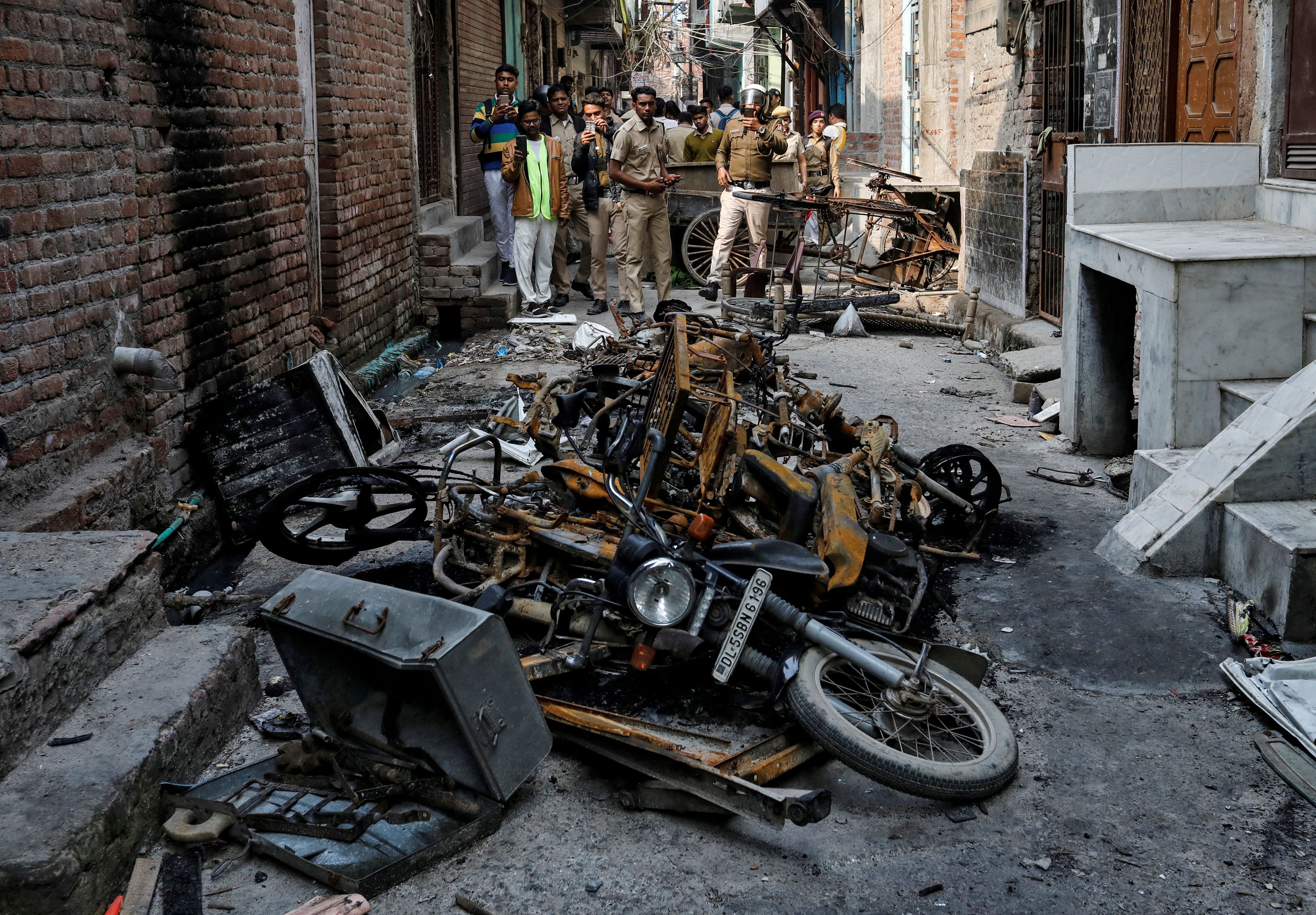 Police in New Delhi photograph burnt out properties owned by Muslims in a riot-hit area