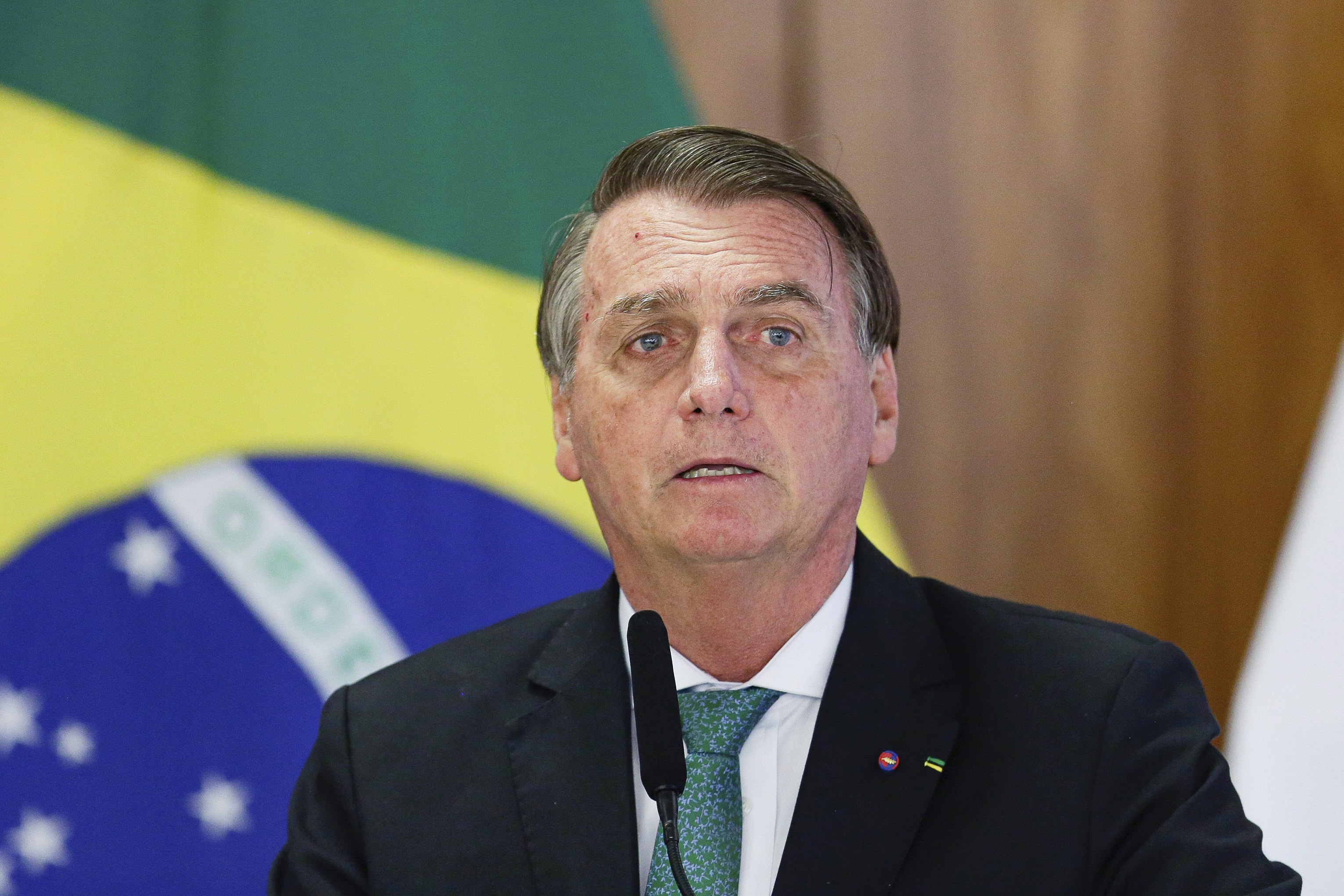 Jair Bolsonaro in front of the Brazilian flag at a press conference