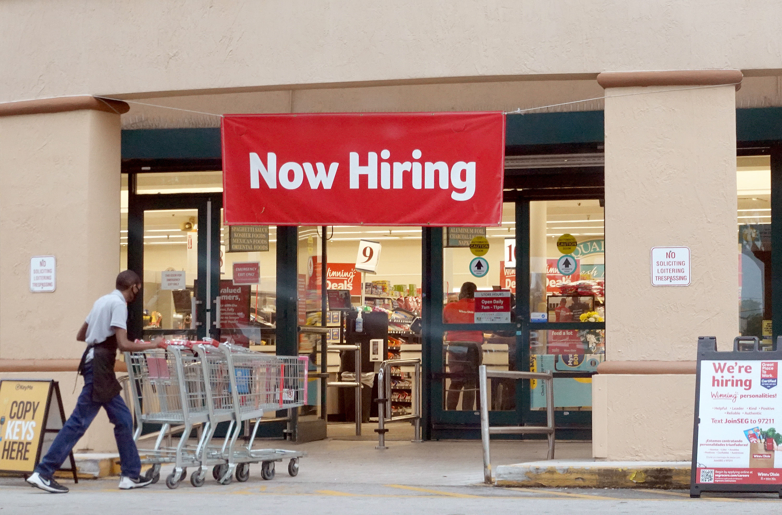A ‘Now Hiring’ sign hangs near the entrance to a Winn-Dixie Supermarket in Hallandale, Florida