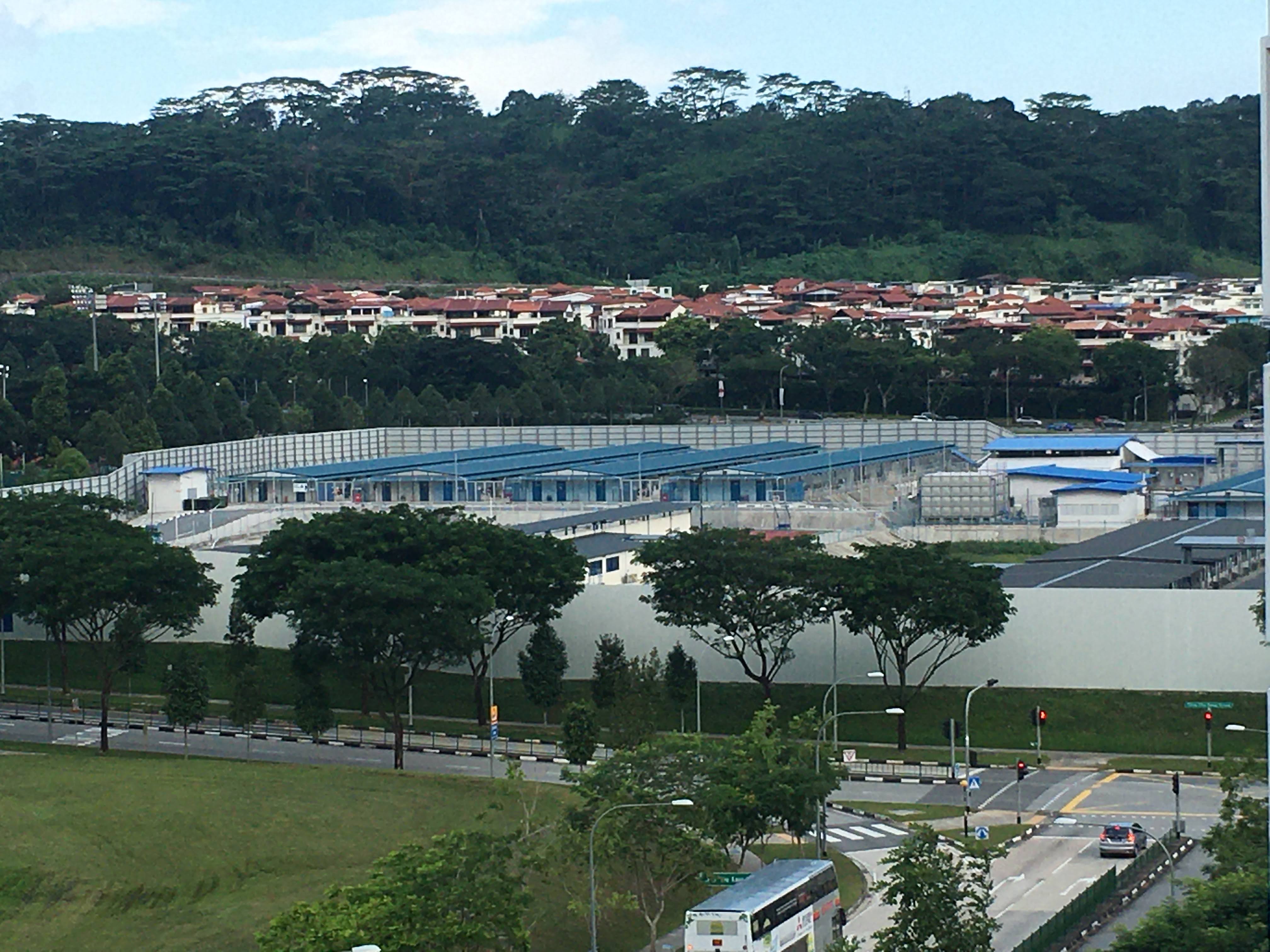 The dormitories are hidden away from the rest of Singapore behind a grey perimeter wall. The workers who live there continue to live under heavy restrictions on their movement [Al Jazeera]