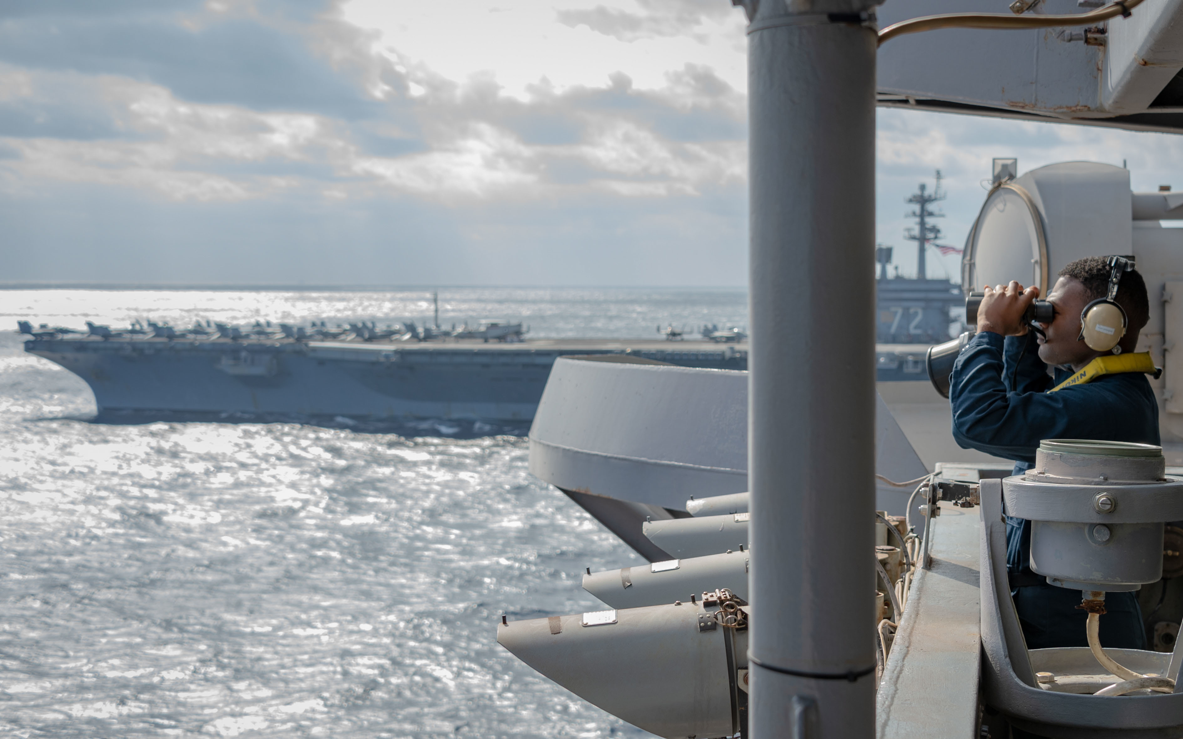 A sailor on the bridge of the USS Carl Vinson looks through binoculars during exercises in the South China Sea