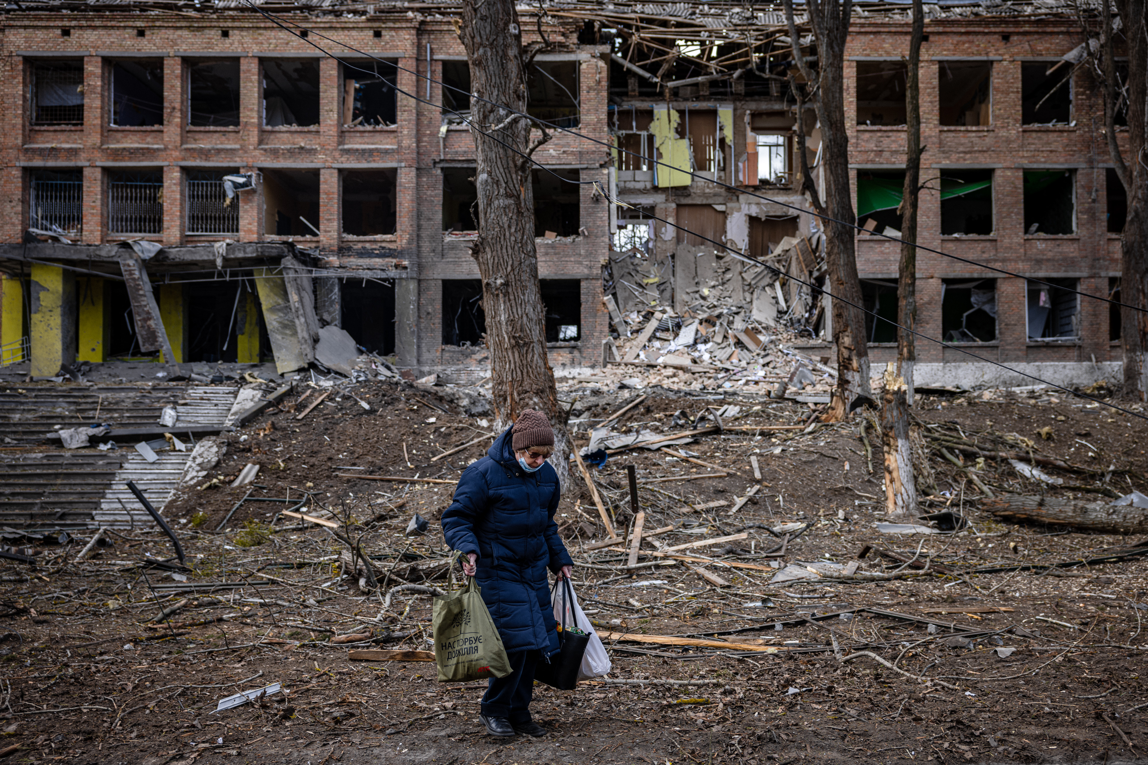 A woman walks in front of a destroyed building after a Russian missile attack in Vasylkiv, near Kyiv