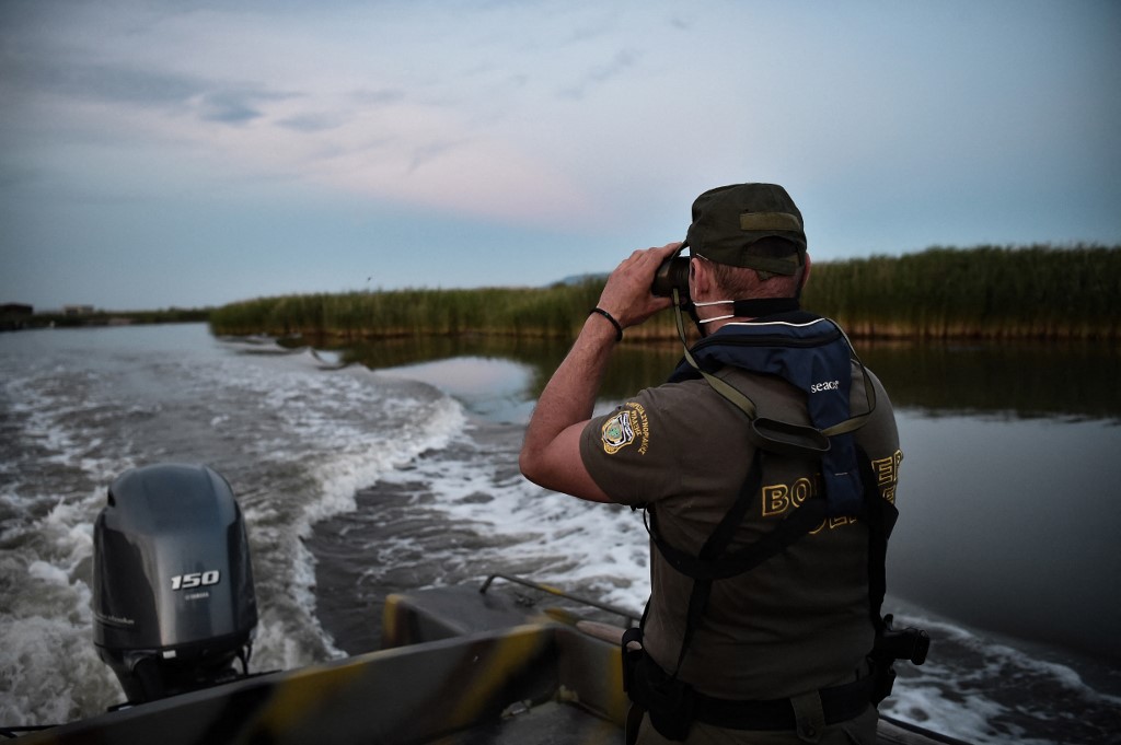In this file image, a police officer patrols the delta of the Evros River on a boat, near Alexandroupoli, along the Greece-Turkey border. The Greek state has deployed an anti-migration arsenal including cameras, radar and a 40-kilometre (25-mile) steel fence over five metres high