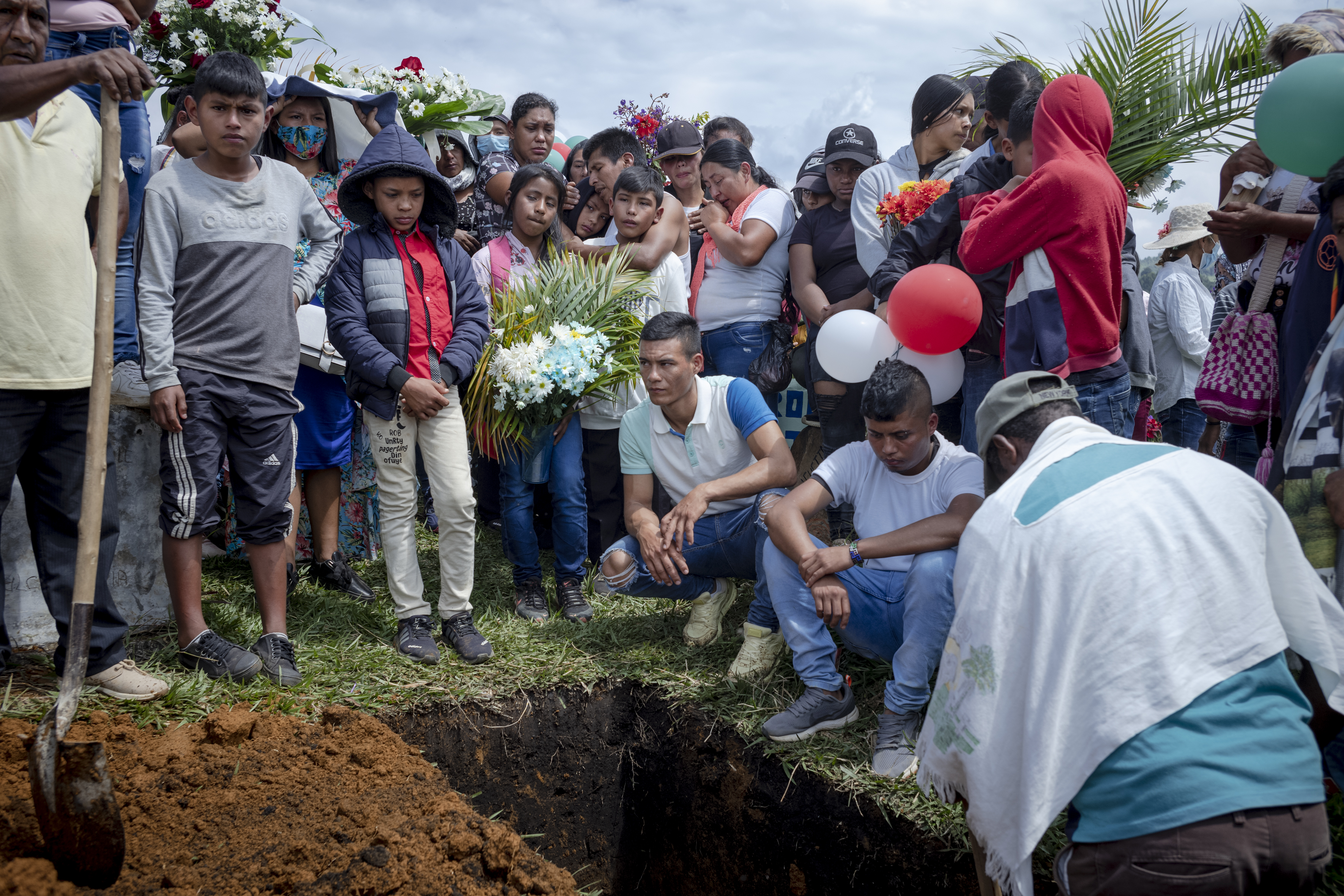 Breiner David's relatives, adults and children, look down into the hole where his coffin lies.