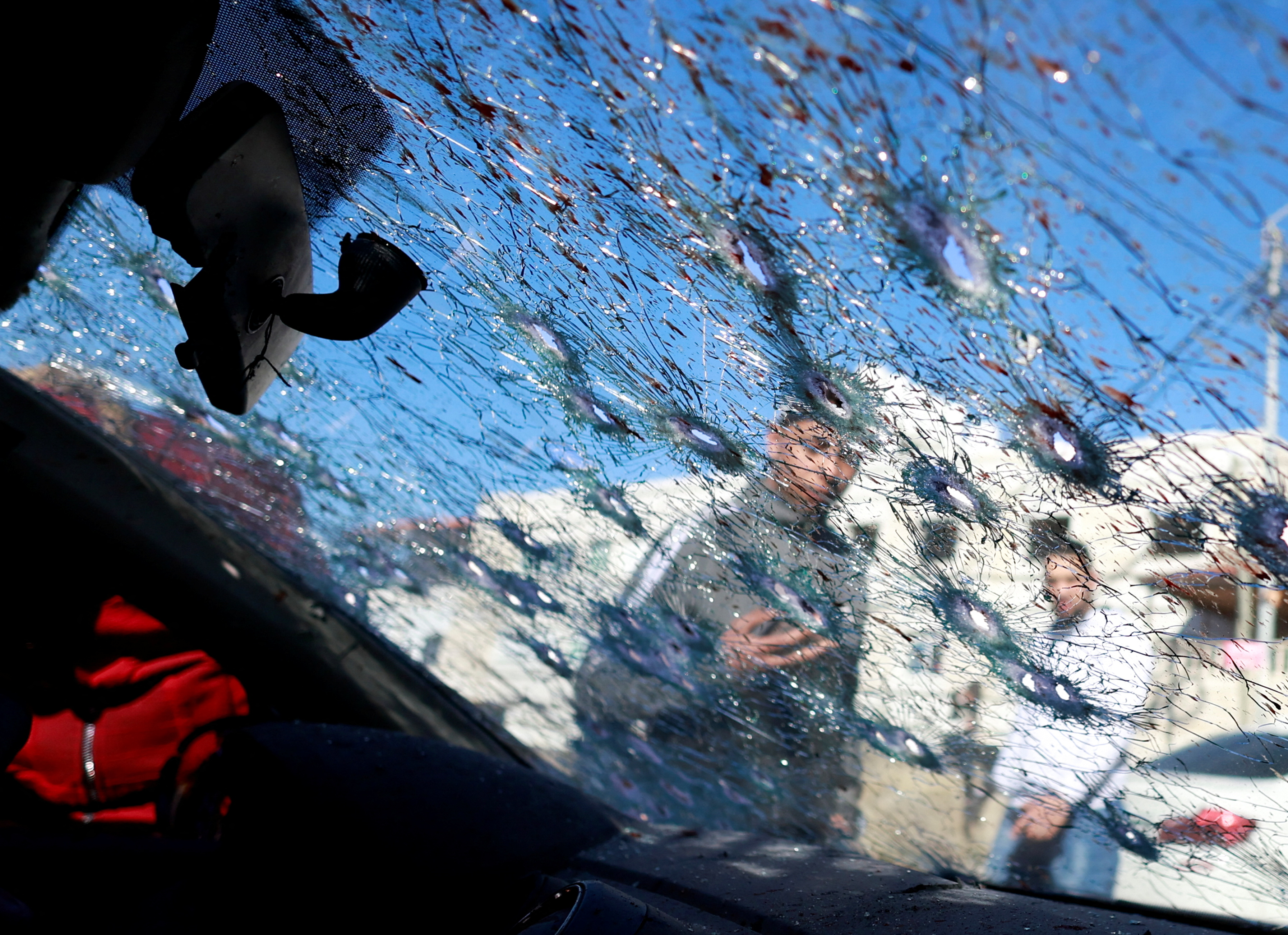 People look at a cracked windscreen with bullet holes at the scene where three Palestinian gunmen were killed by Israeli forces, in Nablus