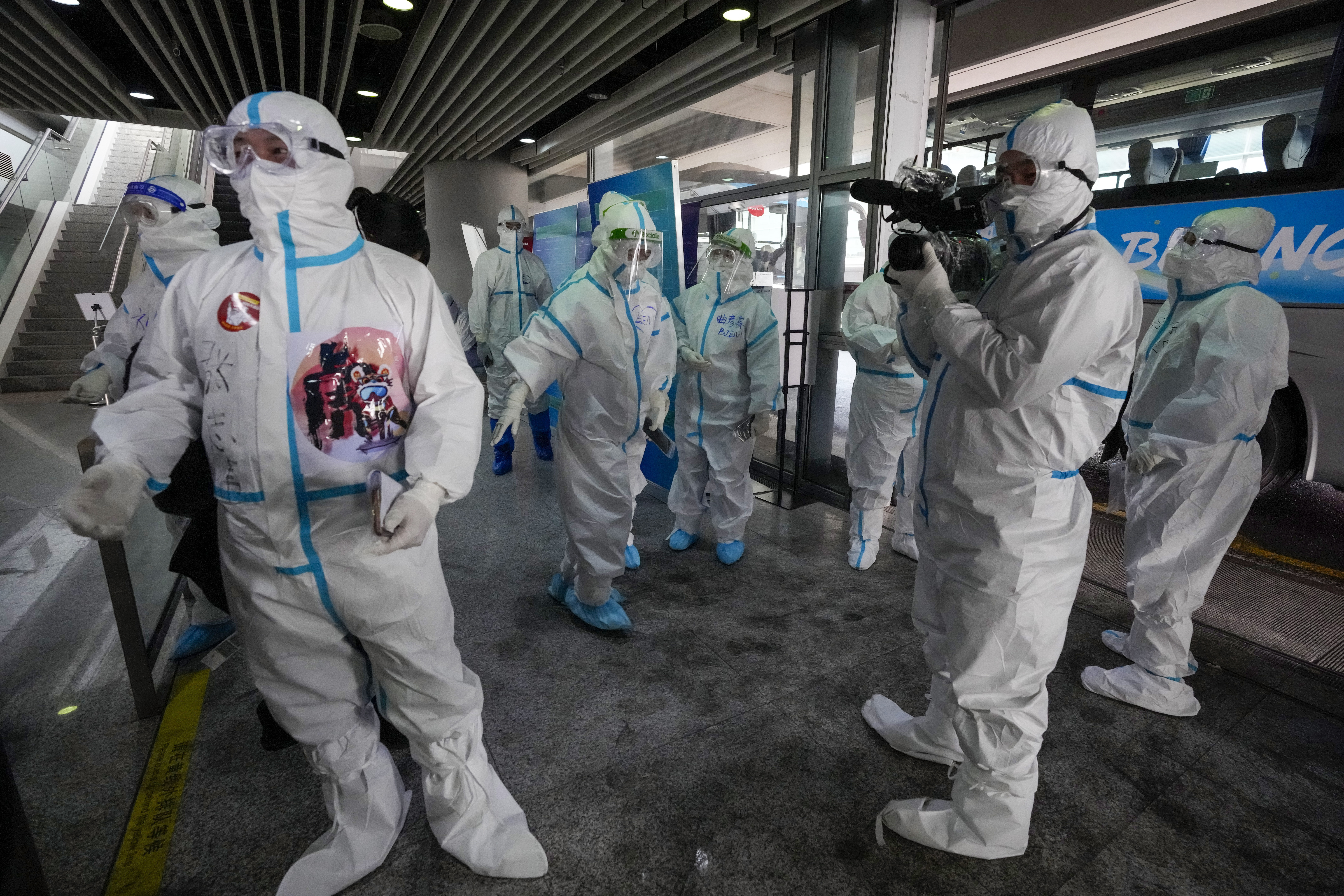 Olympic workers greet members of the media as Beijing 2022 crew films them at the Beijing Capital International Airport ahead of the 2022 Winter Olympics, Sunday, Jan. 30, 2022, in Beijing.