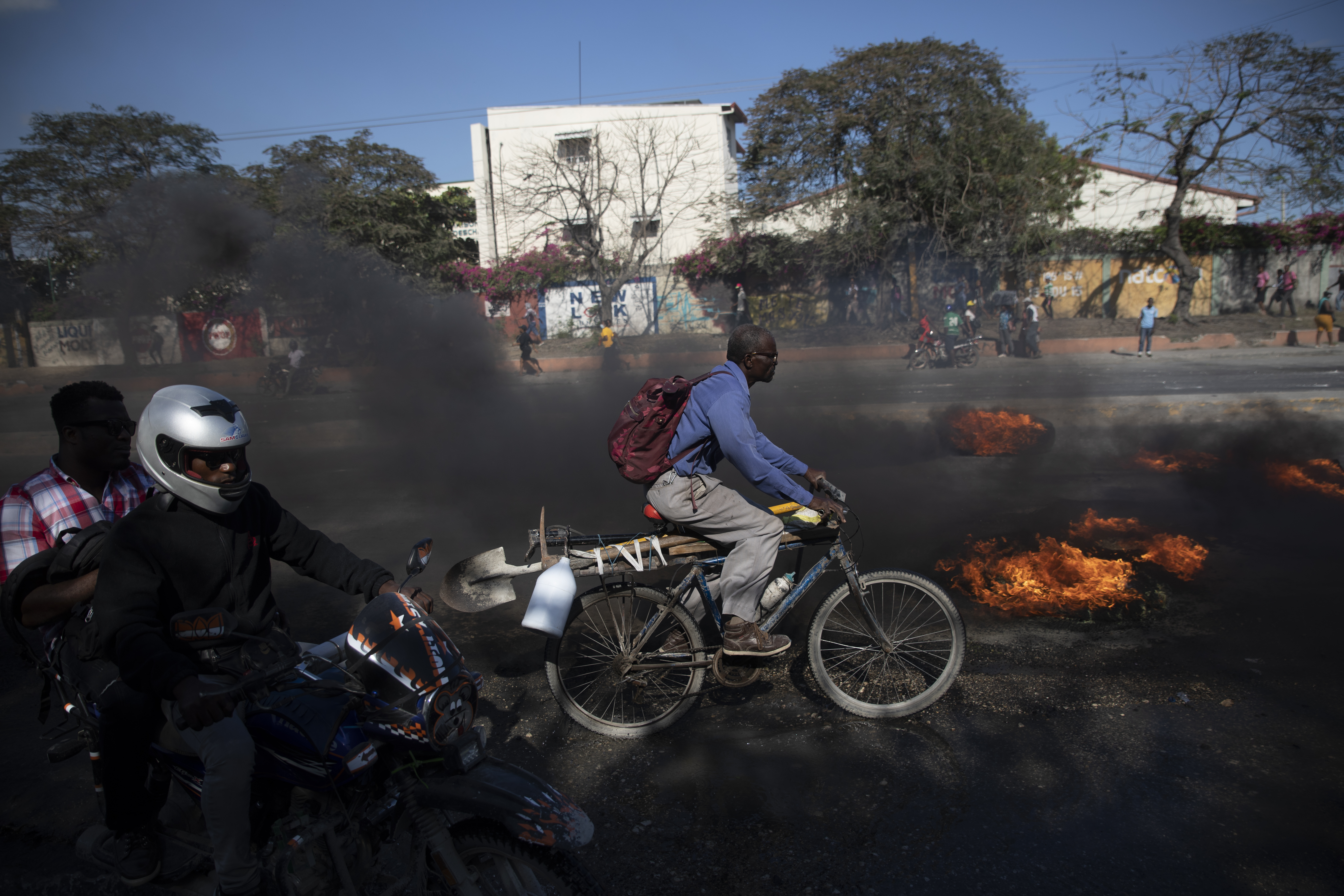 A bicyclist pedals past burning tires set on fire by factory workers demanding a salary increase, in Port-au-Prince, Haiti