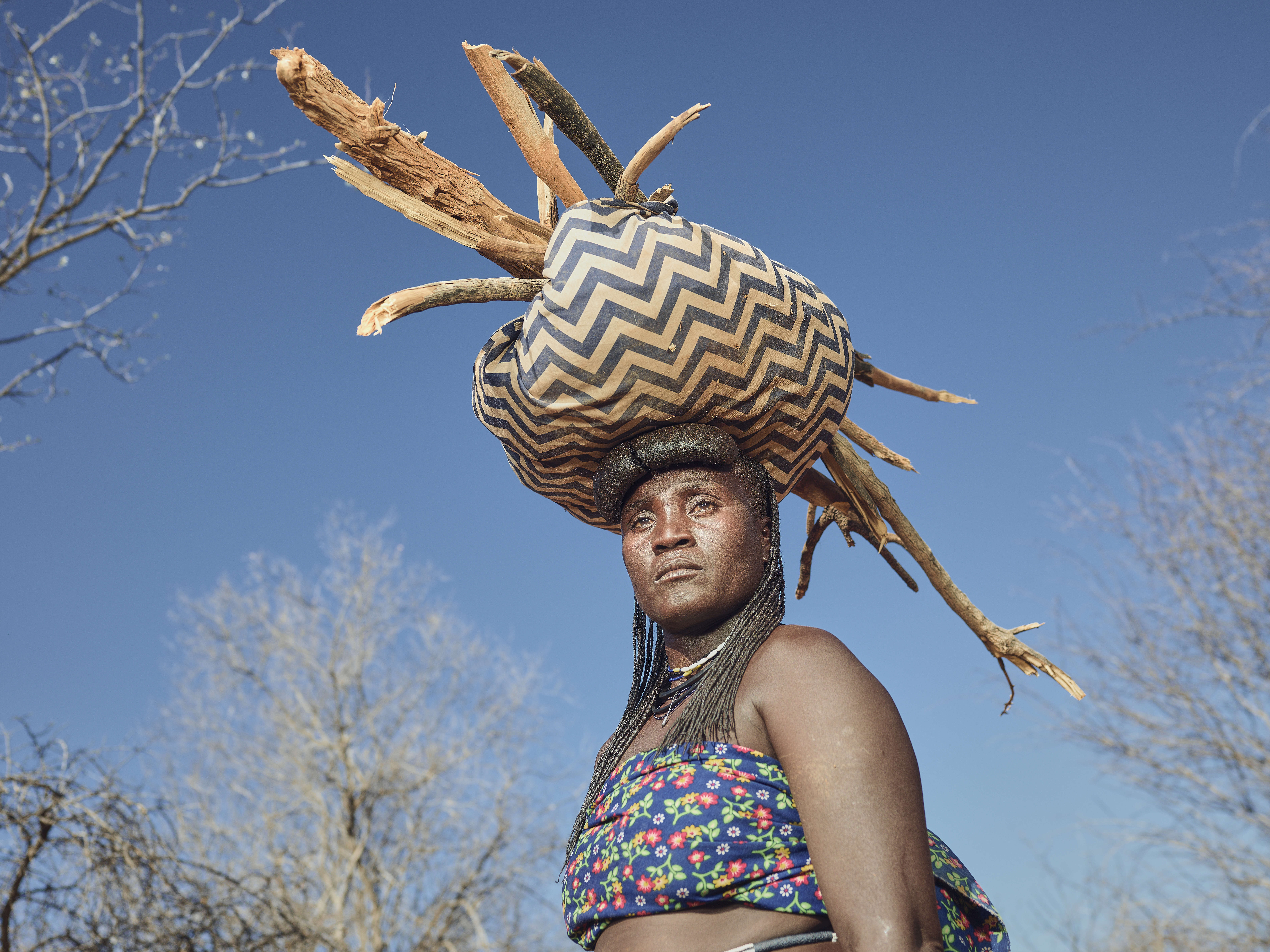 A photo of a woman with a bag and twigs on her head.