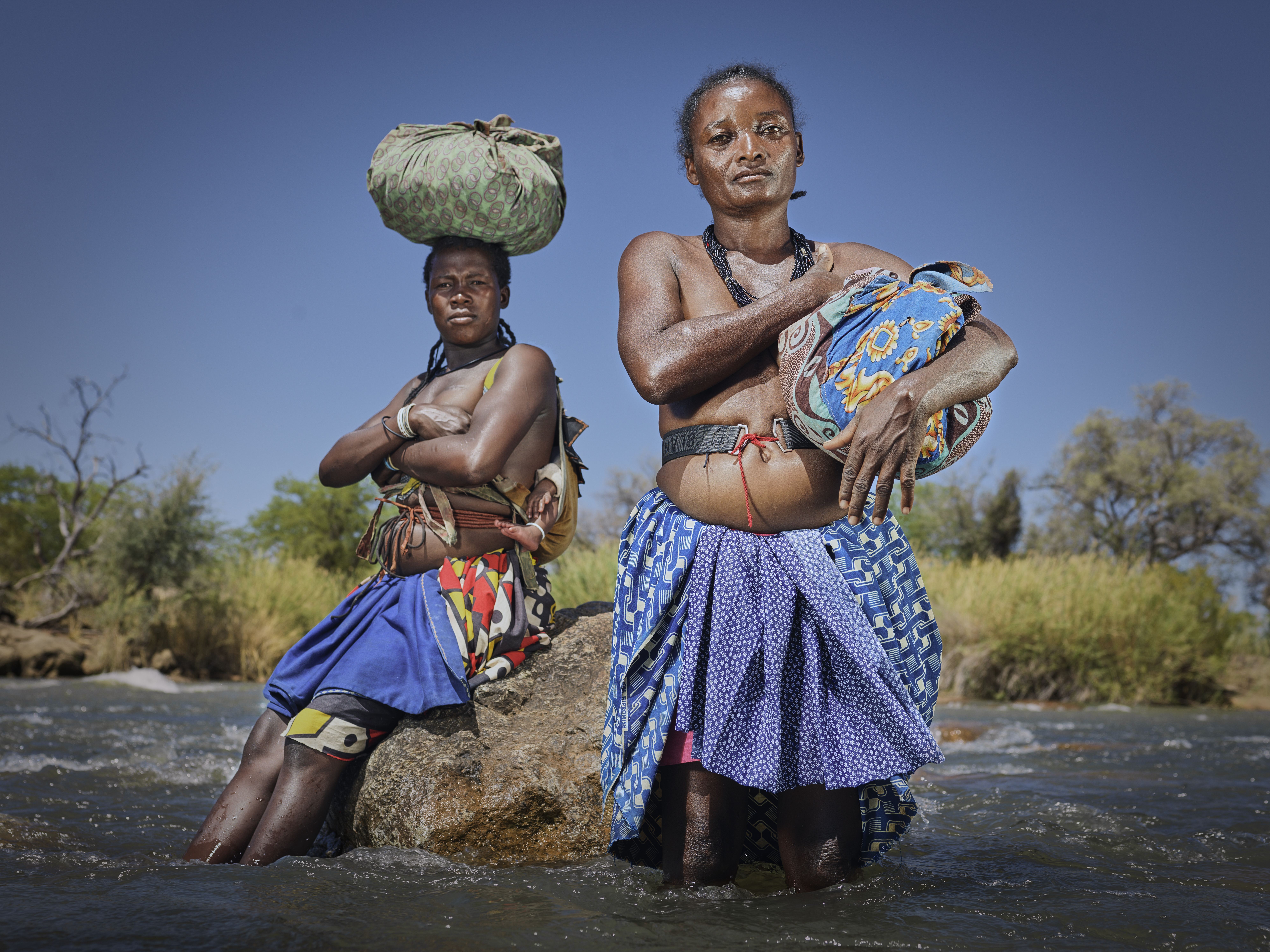 A photo of two women standing in a river.