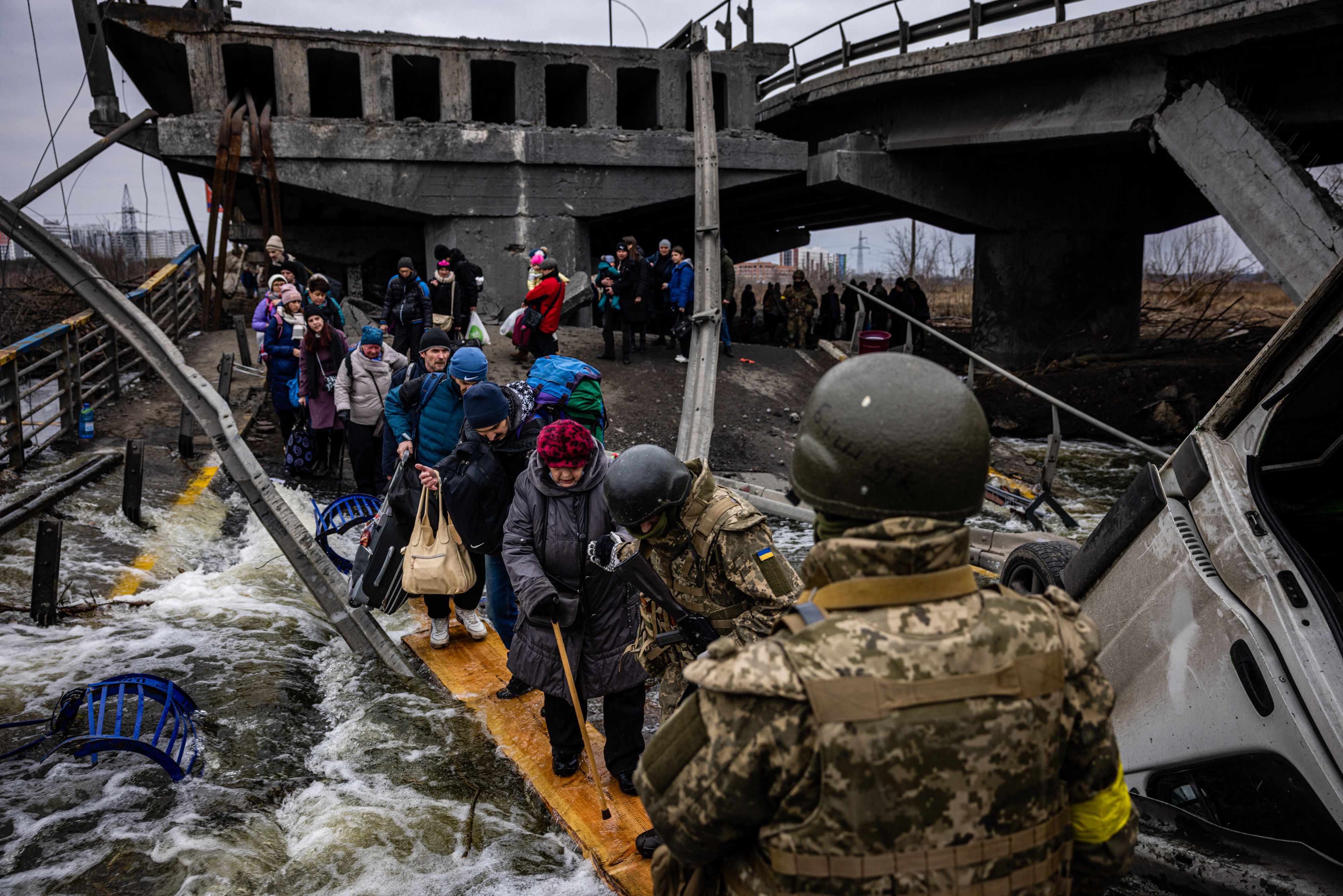 Evacuees cross a destroyed bridge as they flee the city of Irpin, northwest of Kyiv
