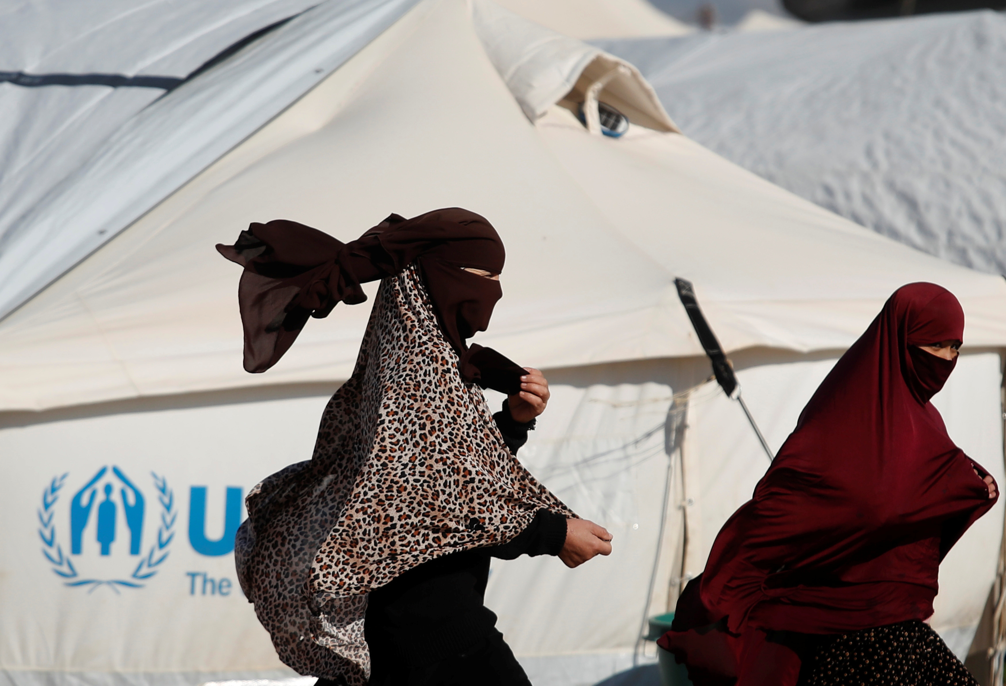 Women walk past a tent in al-Hol camp, Syria, January 8, 2020