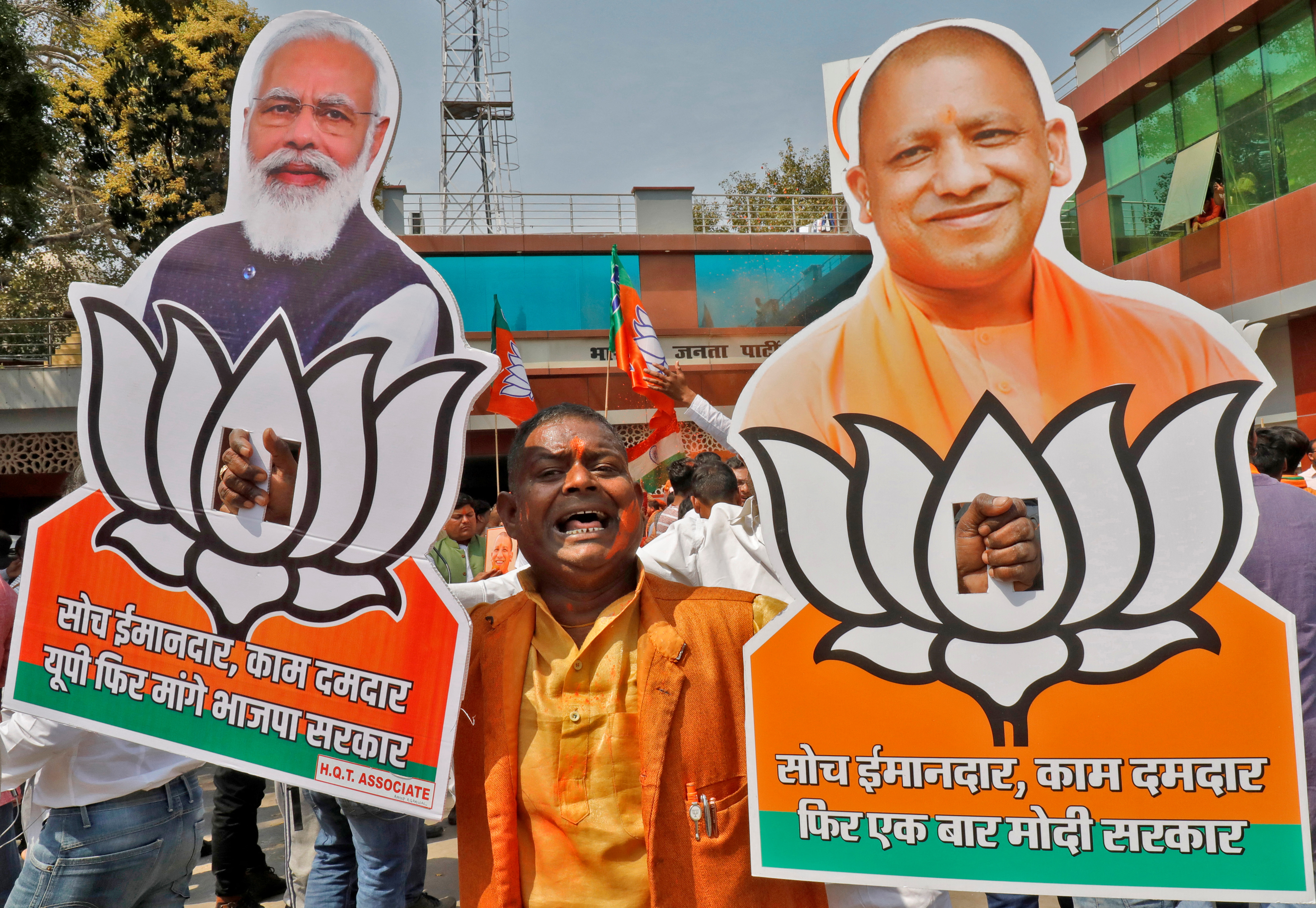 A man displays cutouts of Adityanath and Modi as he celebrates Uttar Pradesh poll results outside the BJP office in Lucknow