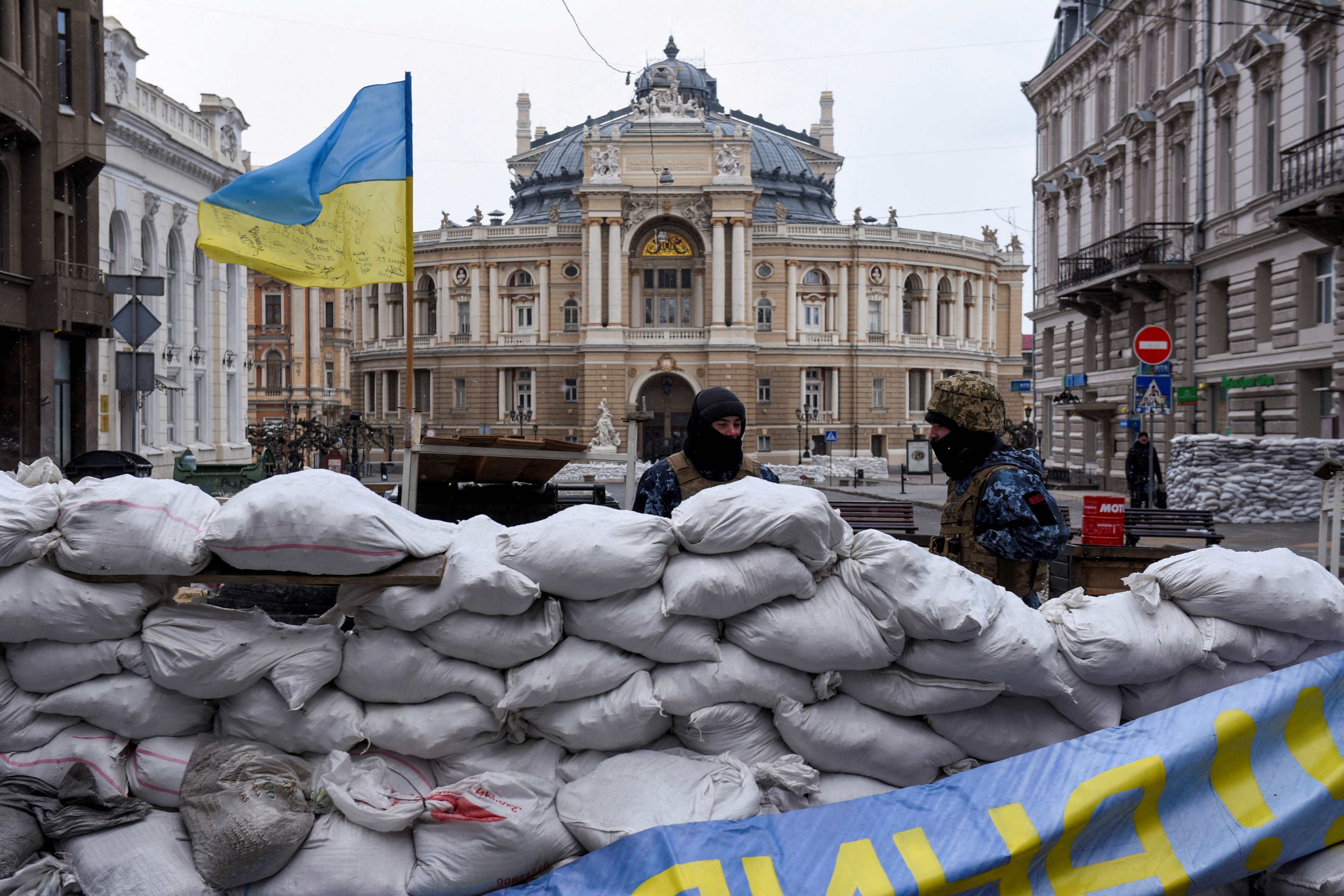 Soldiers stand guard behind a barricade, with the Odesa National Academic Opera and Ballet Theatre seen in the background