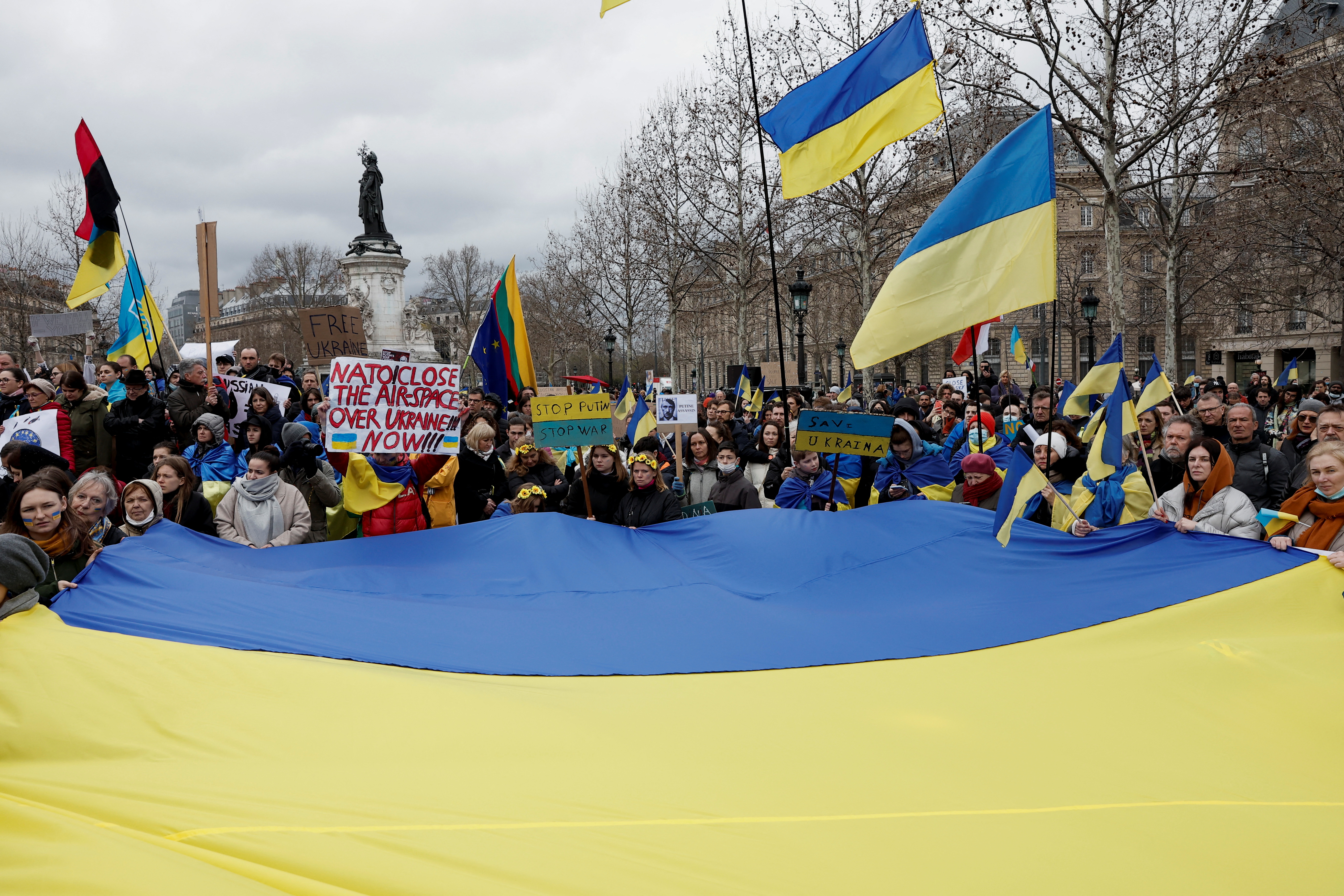 Demonstrators hold a giant Ukrainian flag as they gather on the Place de la Republique square to protest against the Russian invasion of Ukraine, in Paris,