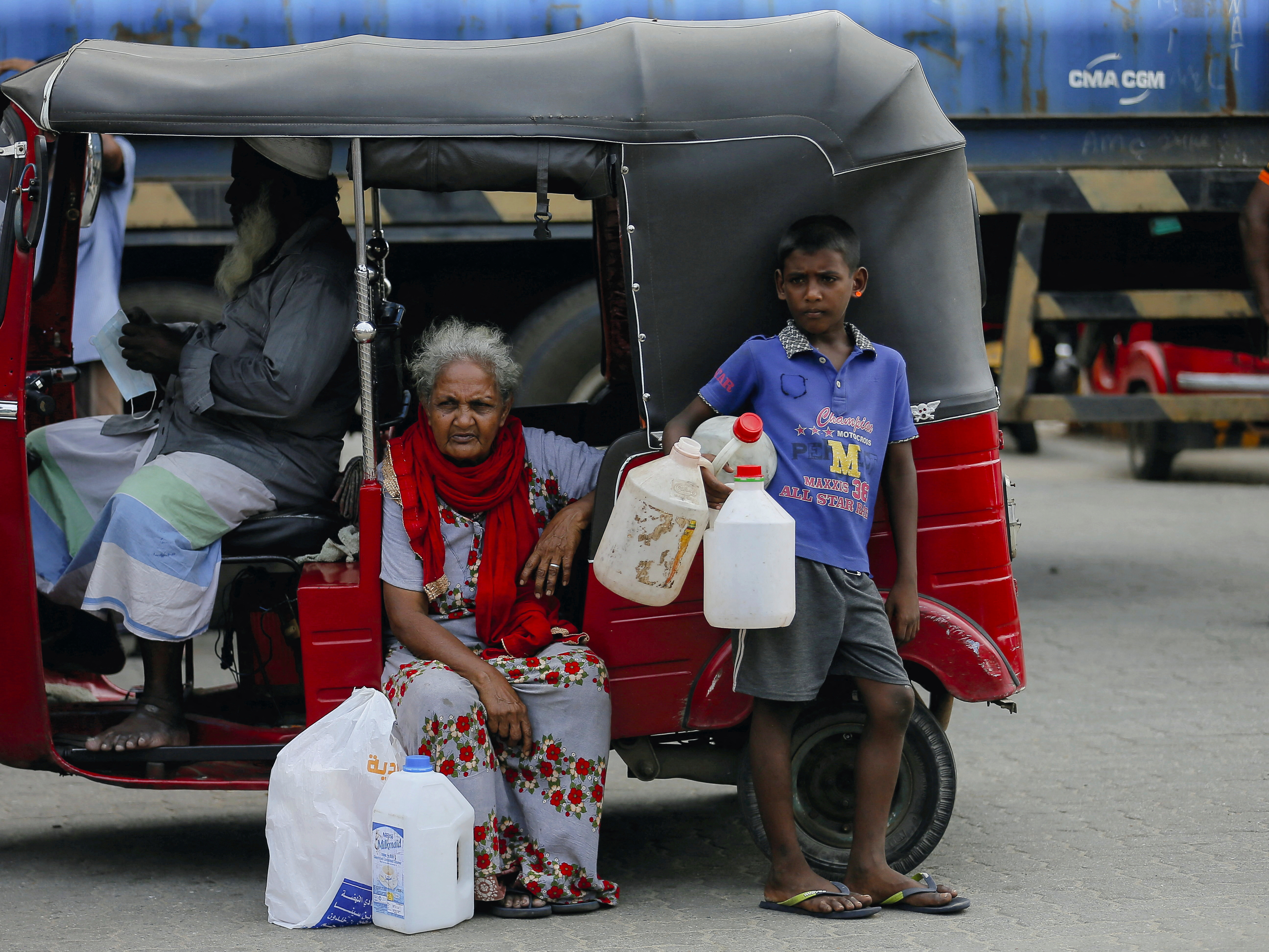 A boy holds empty containers as he waits with his family members to buy kerosene oil in Sri Lanka