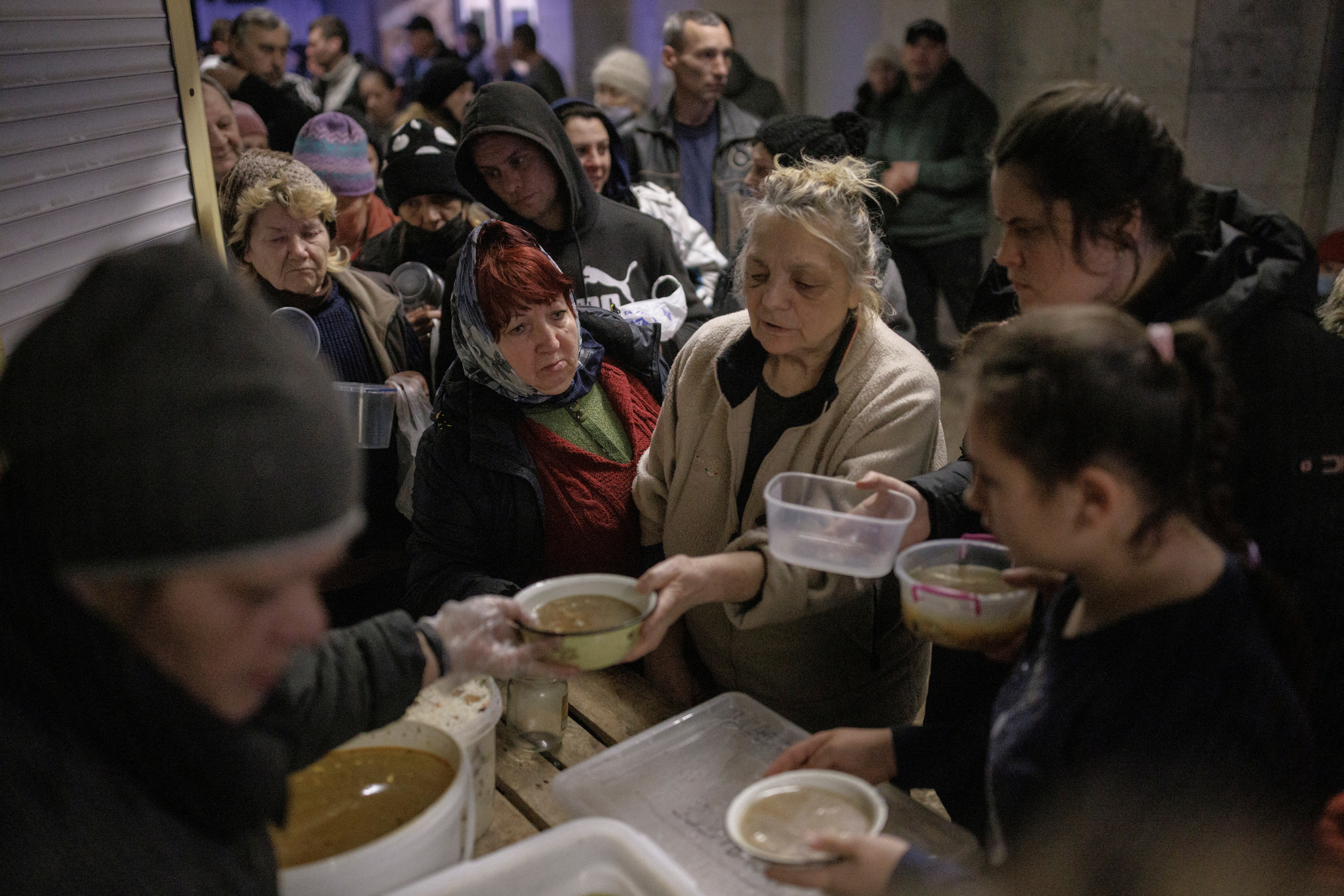 People who are sheltering in a metro station in northern Kharkiv receive food from volunteers. The UK is sending emergency supplies following a request from the government