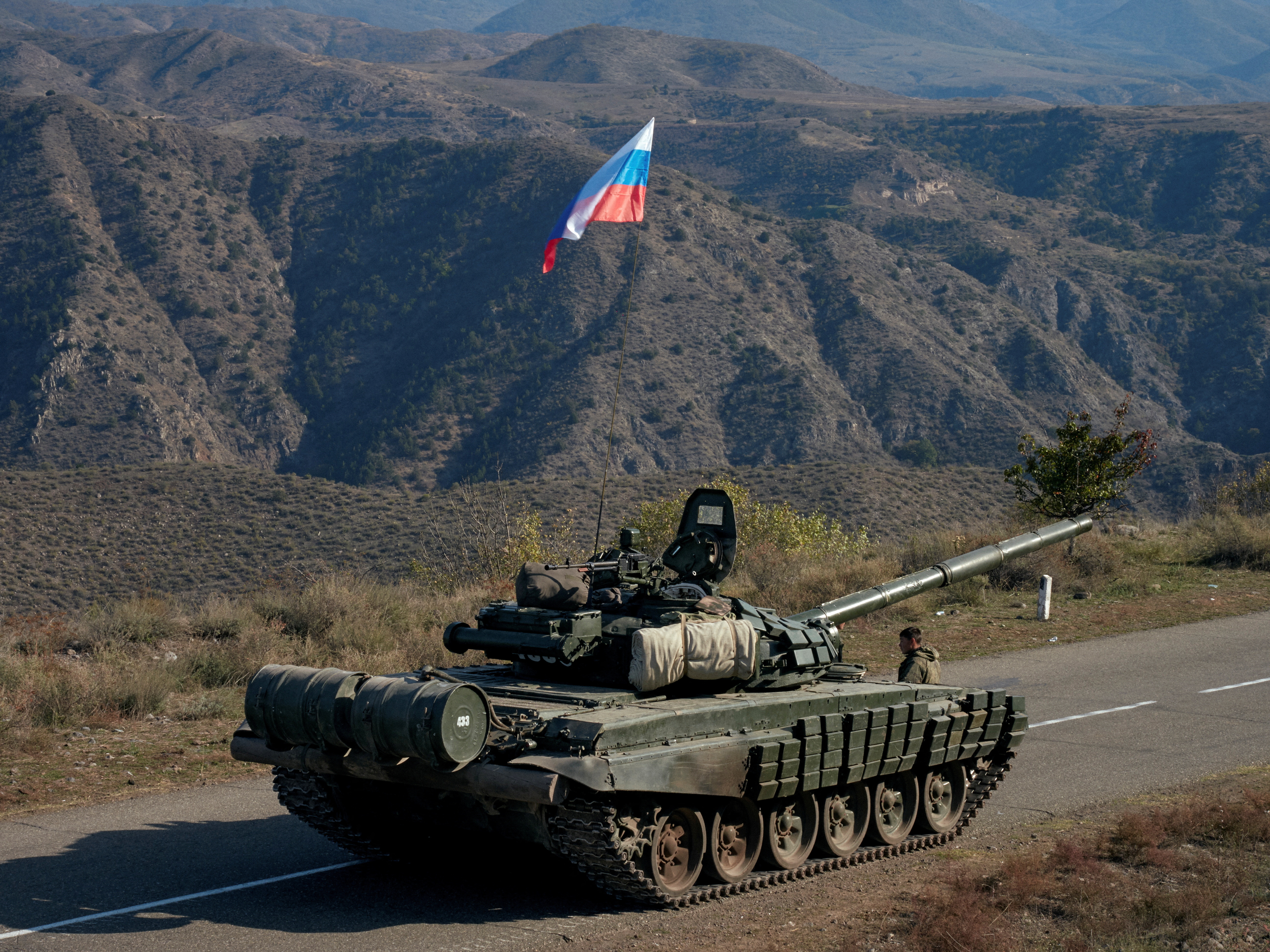 A service member of the Russian peacekeeping troops stands next to a tank near the border with Armenia in the region of Nagorno-Karabakh