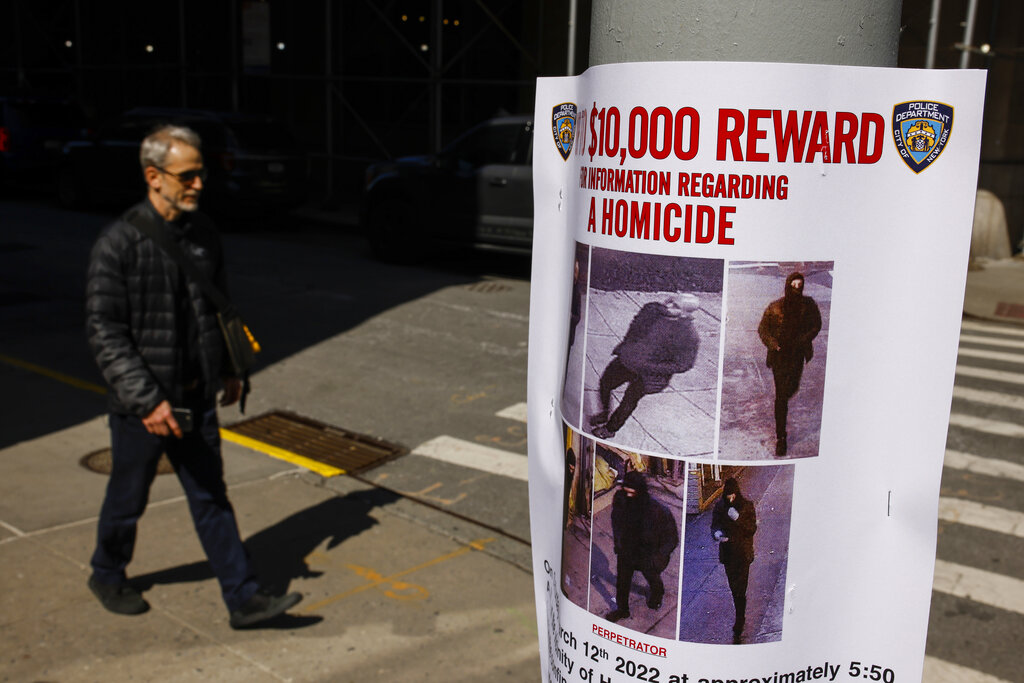 A pedestrian walks past a bulletin posted by NYPD near the place where a homeless person was killed days earlier in lower Manhattan as the search for the gunman was under way