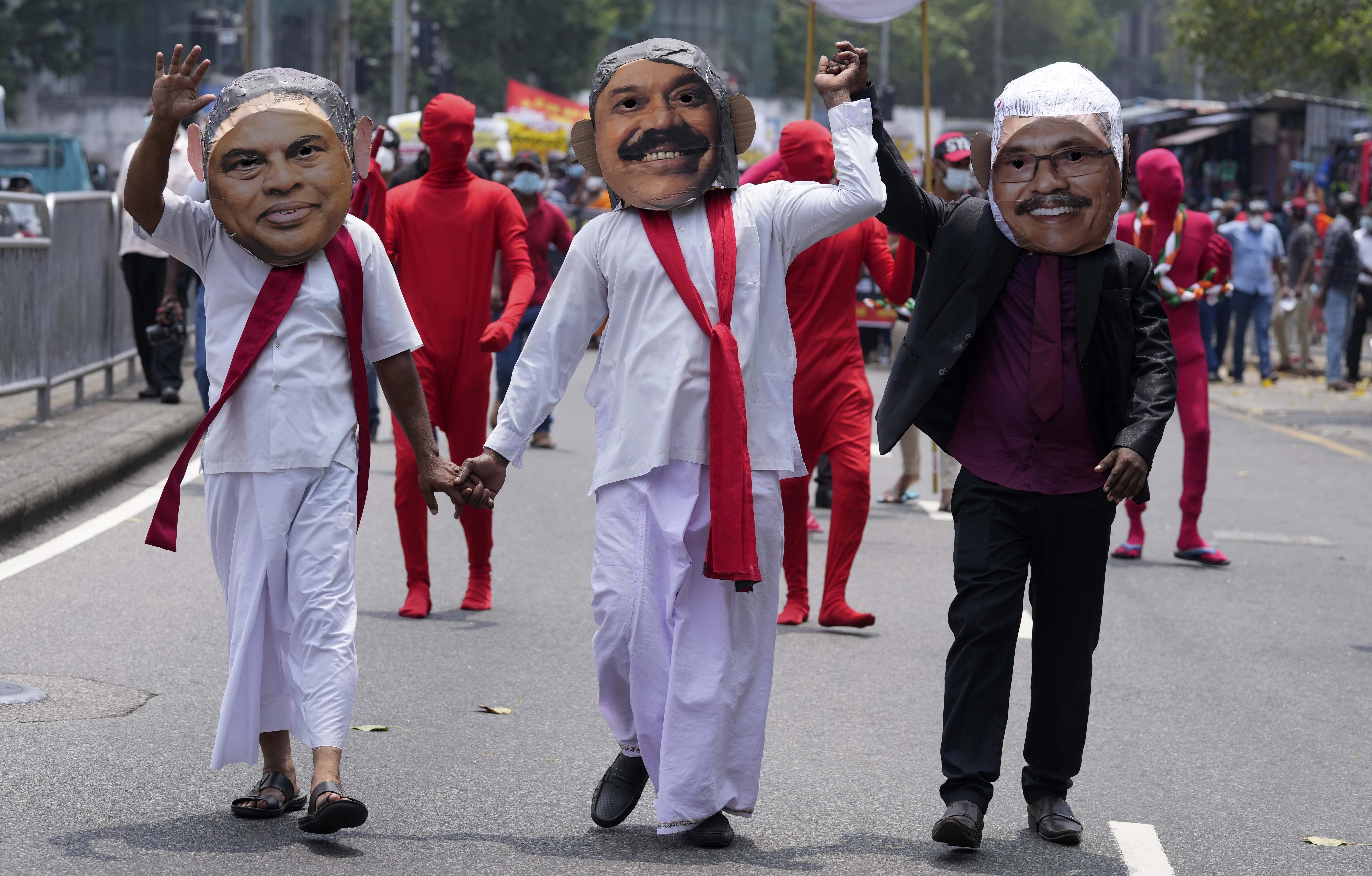 Protesters dressed as President Gotabaya Rajapaksa, right, and his brothers, ex-finance minister Basil, left, and Prime Minister Mahinda walk during a protest in Colombo, Sri Lanka