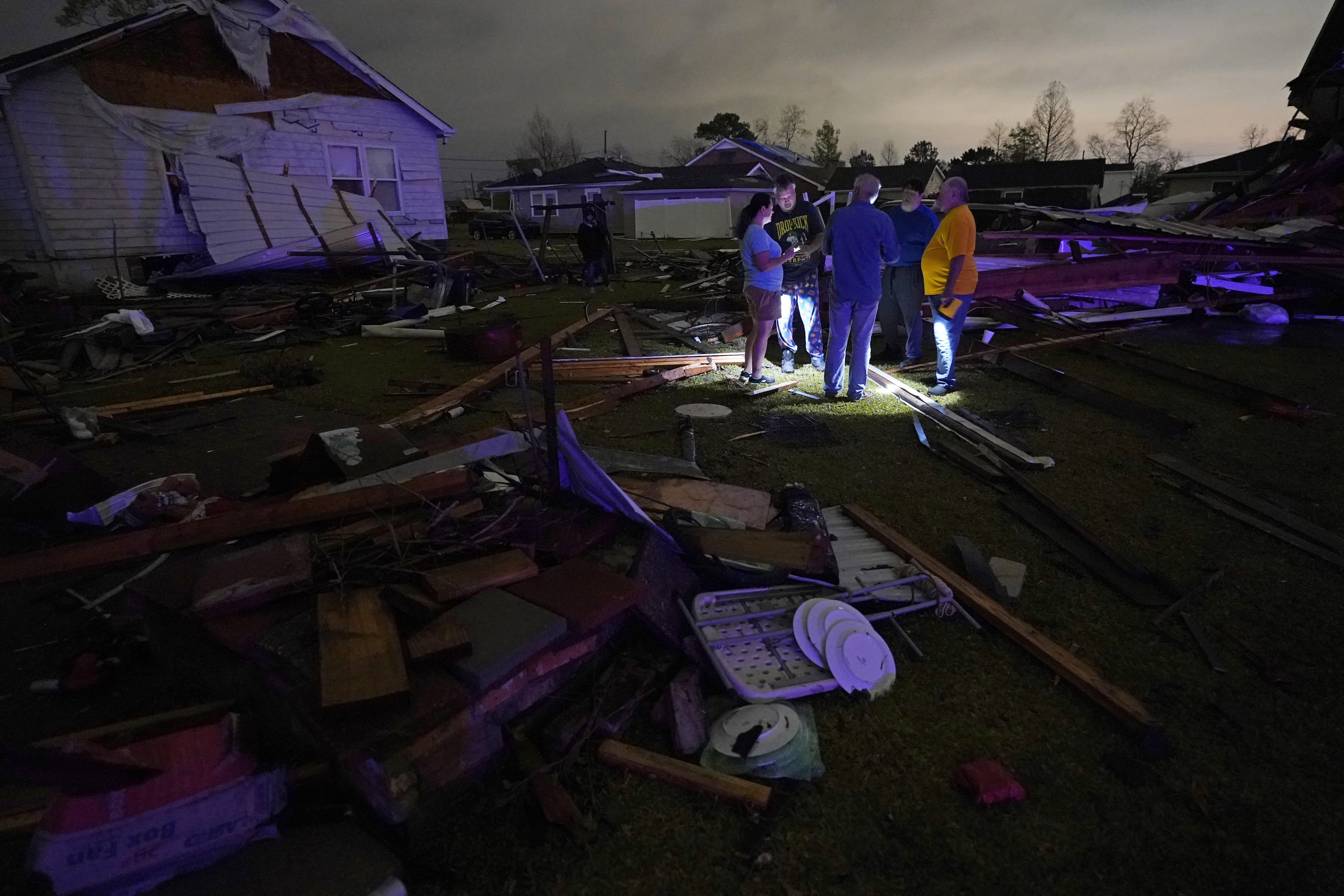 Residents talk among the debris of their damaged homes after a tornado struck the area
