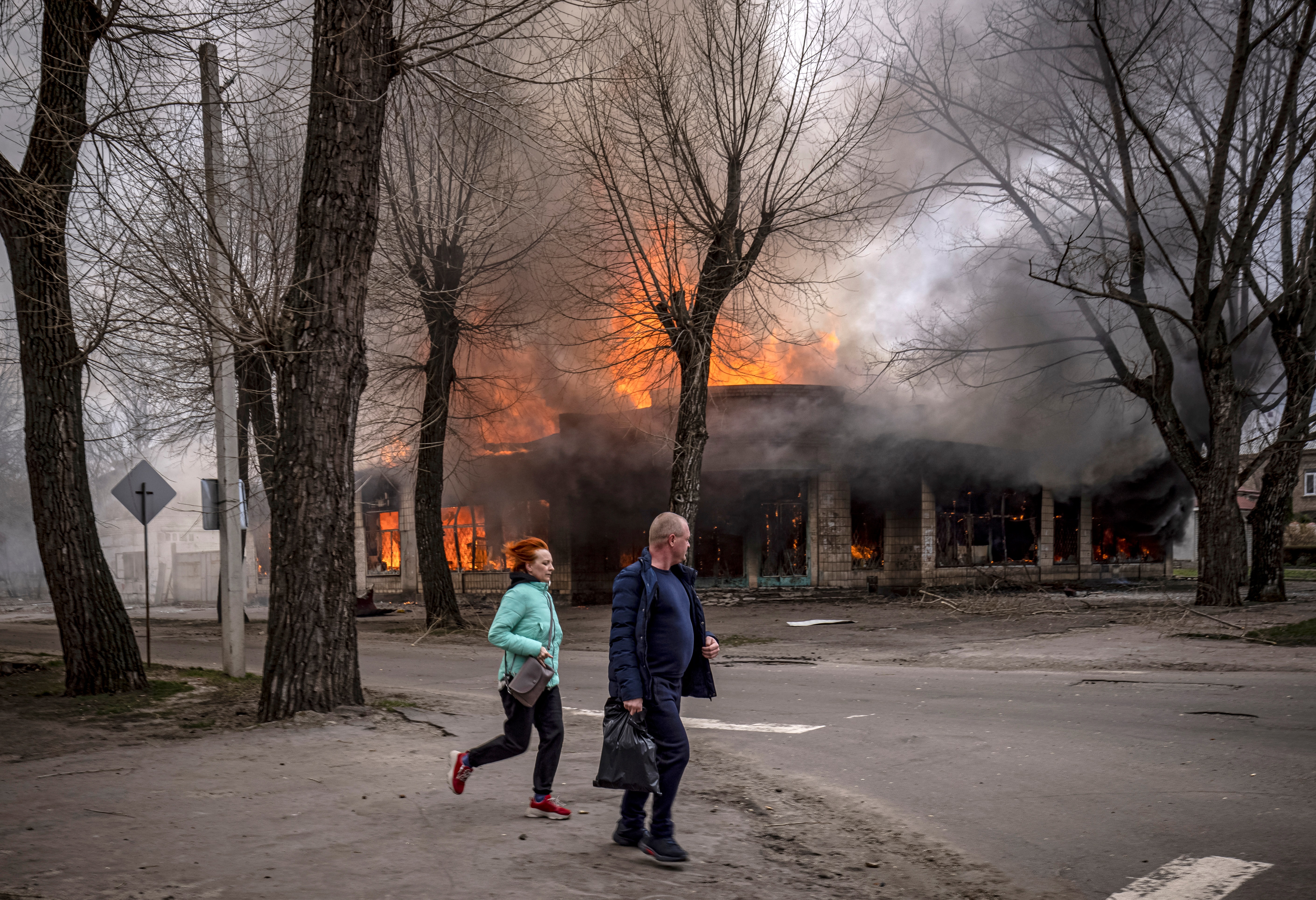Residents run near a burning house following a shelling in Severodonetsk, Donbas region