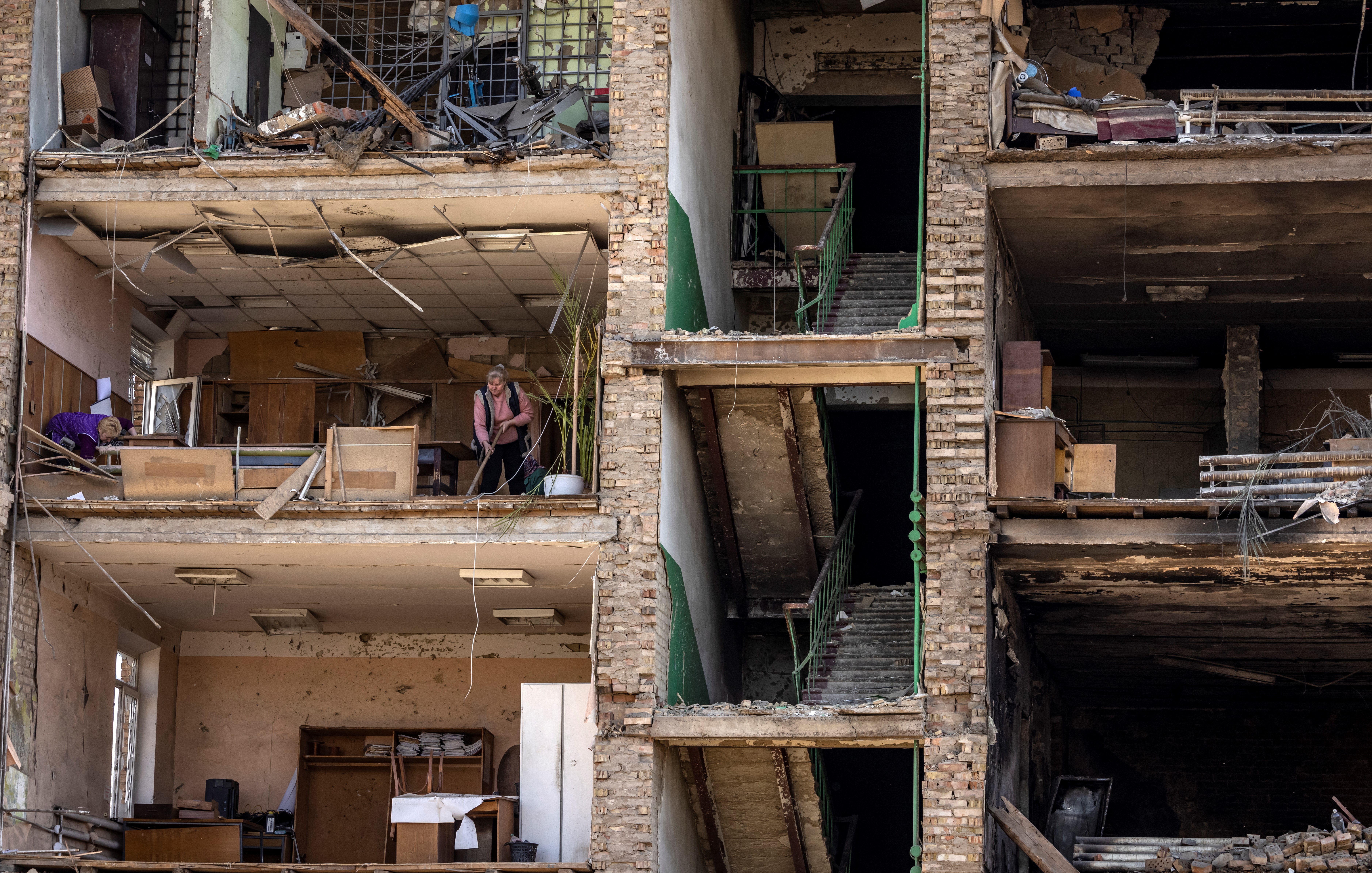 Women clean in a building with a collapsed façade at the Vizar company military-industrial complex, after the site was hit by overnight Russian attacks, in the town of Vyshneve, southwestern suburbs of Kyiv, on April 15, 2022