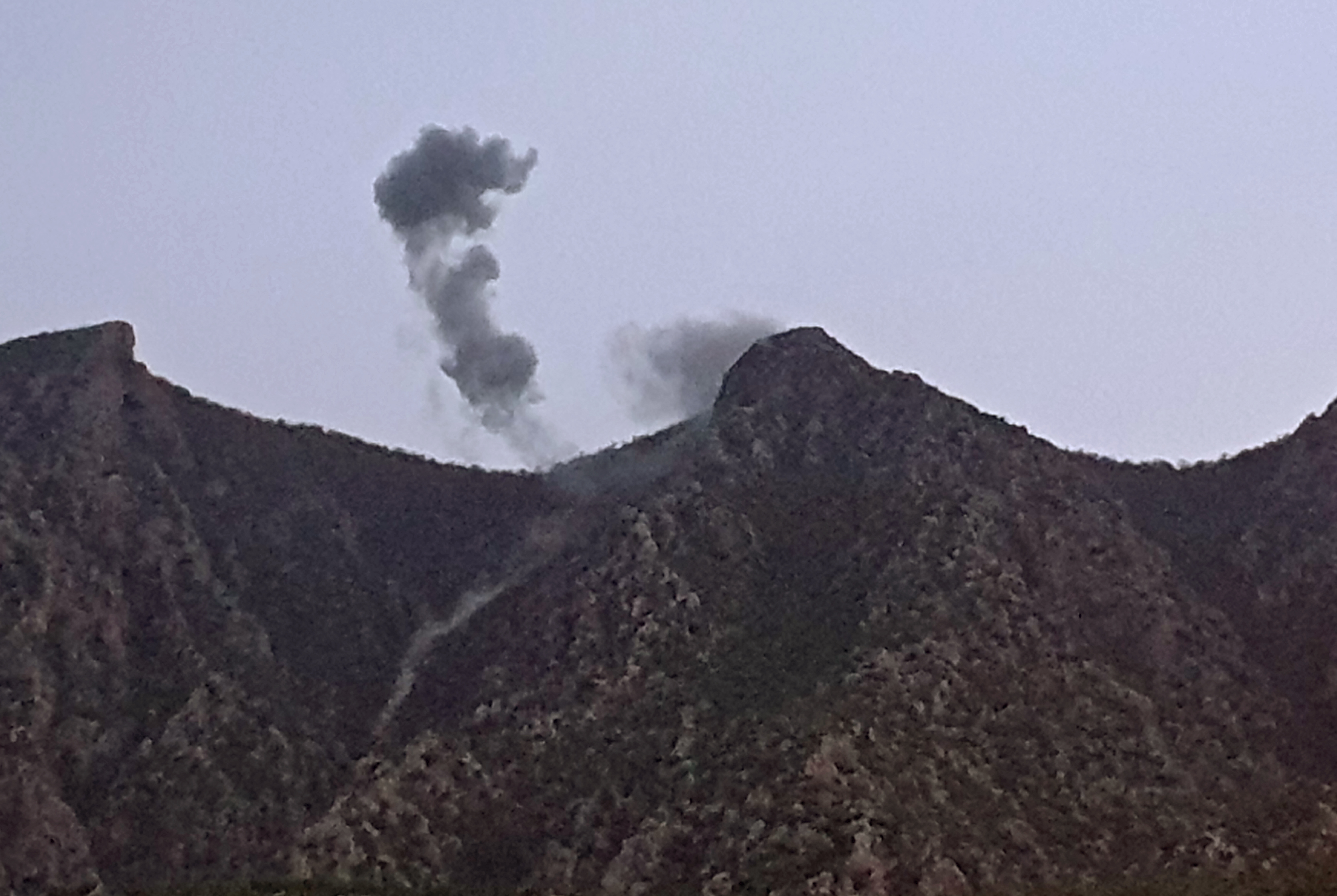 Smoke billowing from behind the mountains of Matin (Jabal Matin) in the town of Chiladze in northern Iraq