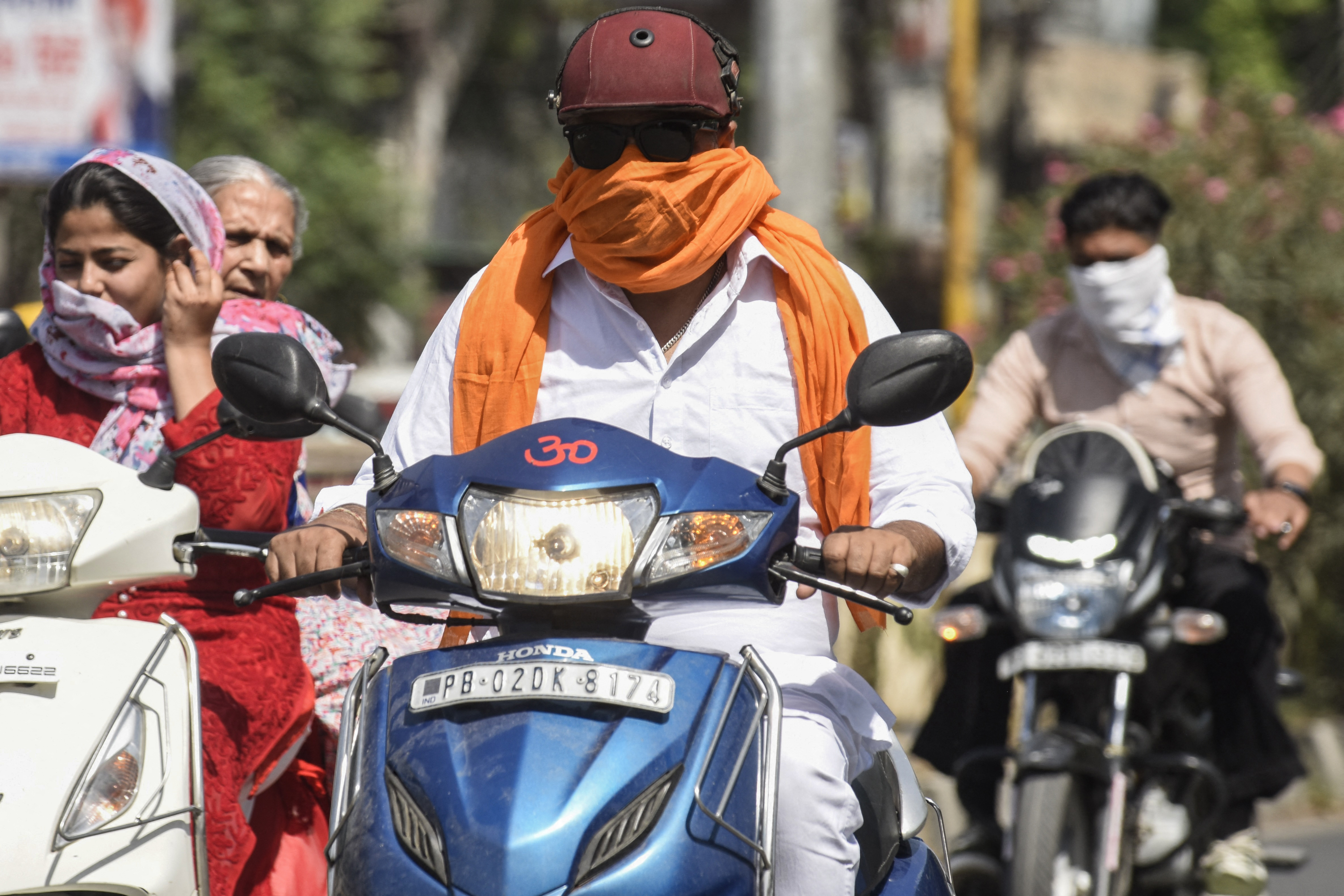 Commuters cover their face with cloth to shelter from the heat in Amritsar, Punjab state