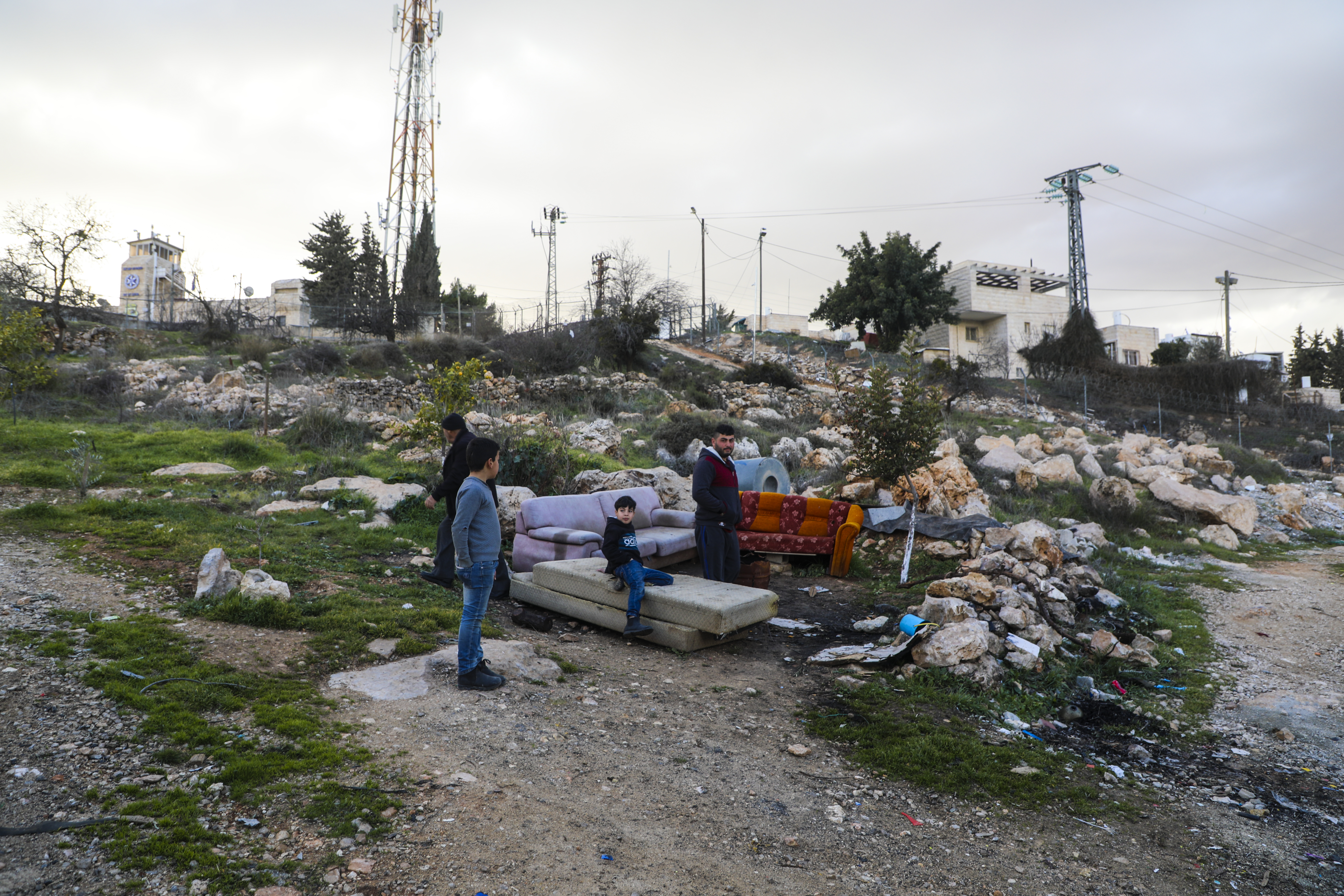 Abu Anan and his children on their land with the settlement outpost of Giv’at Ha’Avot in the background
