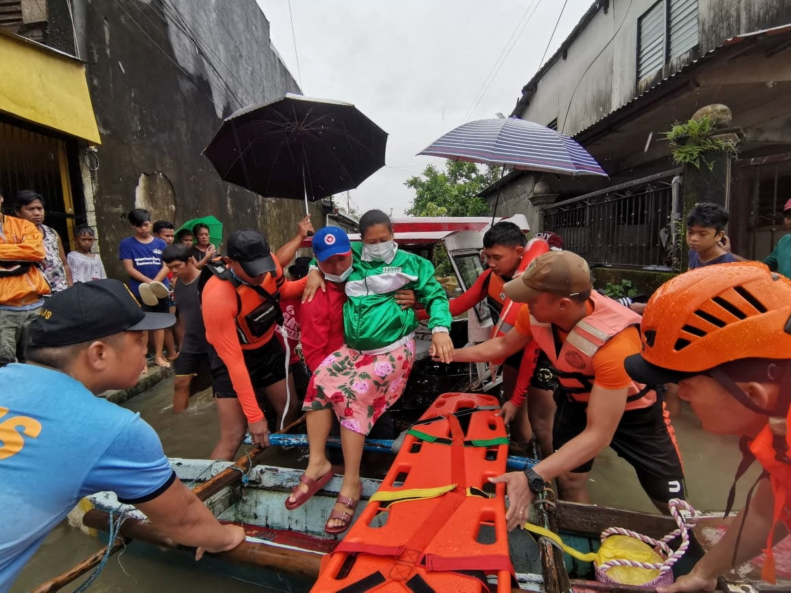 Officials help a woman into a raft amid heavy rain in Leyte province, Philippines.