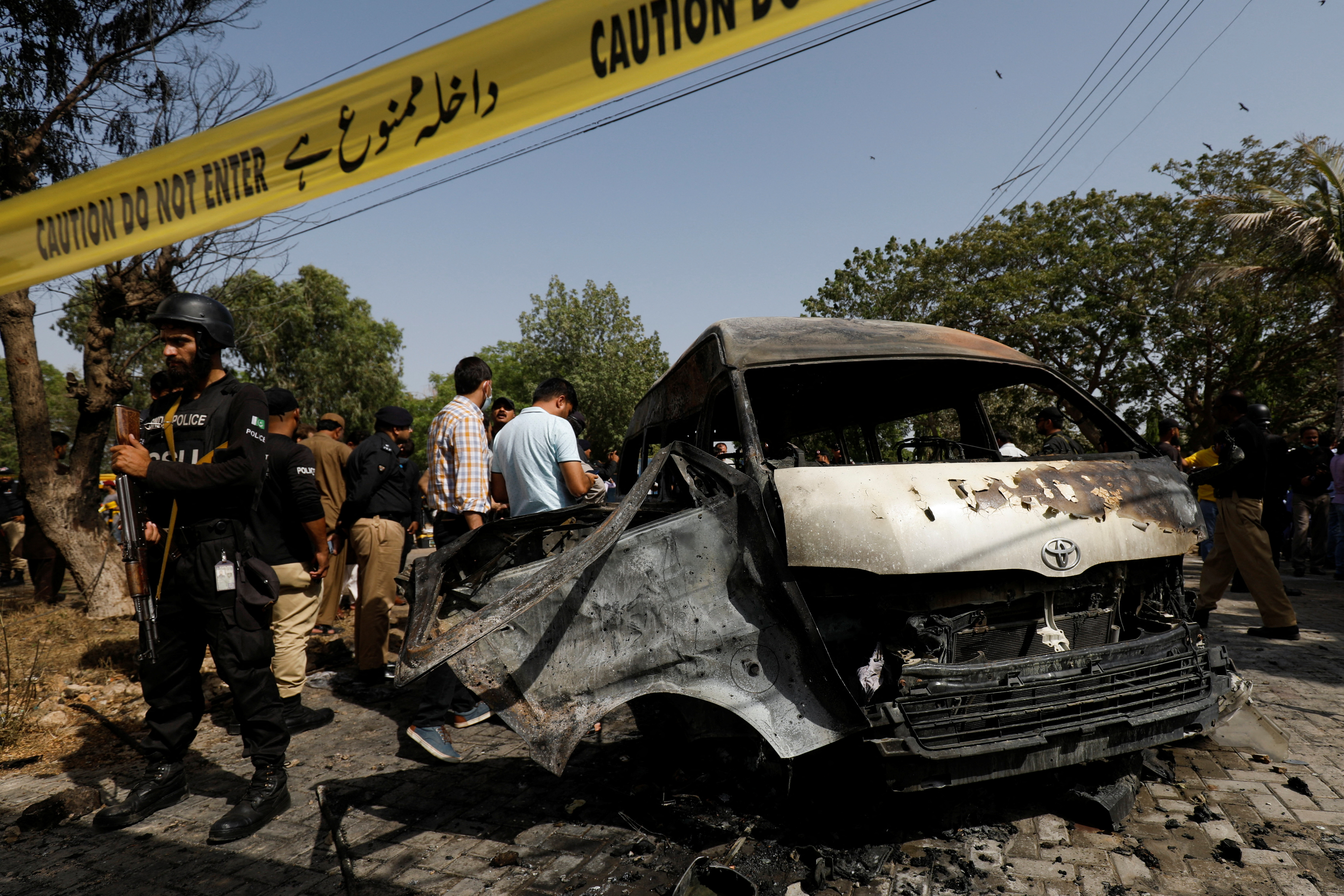 Pakistani officers inspect a passenger van after a suicide blast at the University of Karachi on April 26, 2022