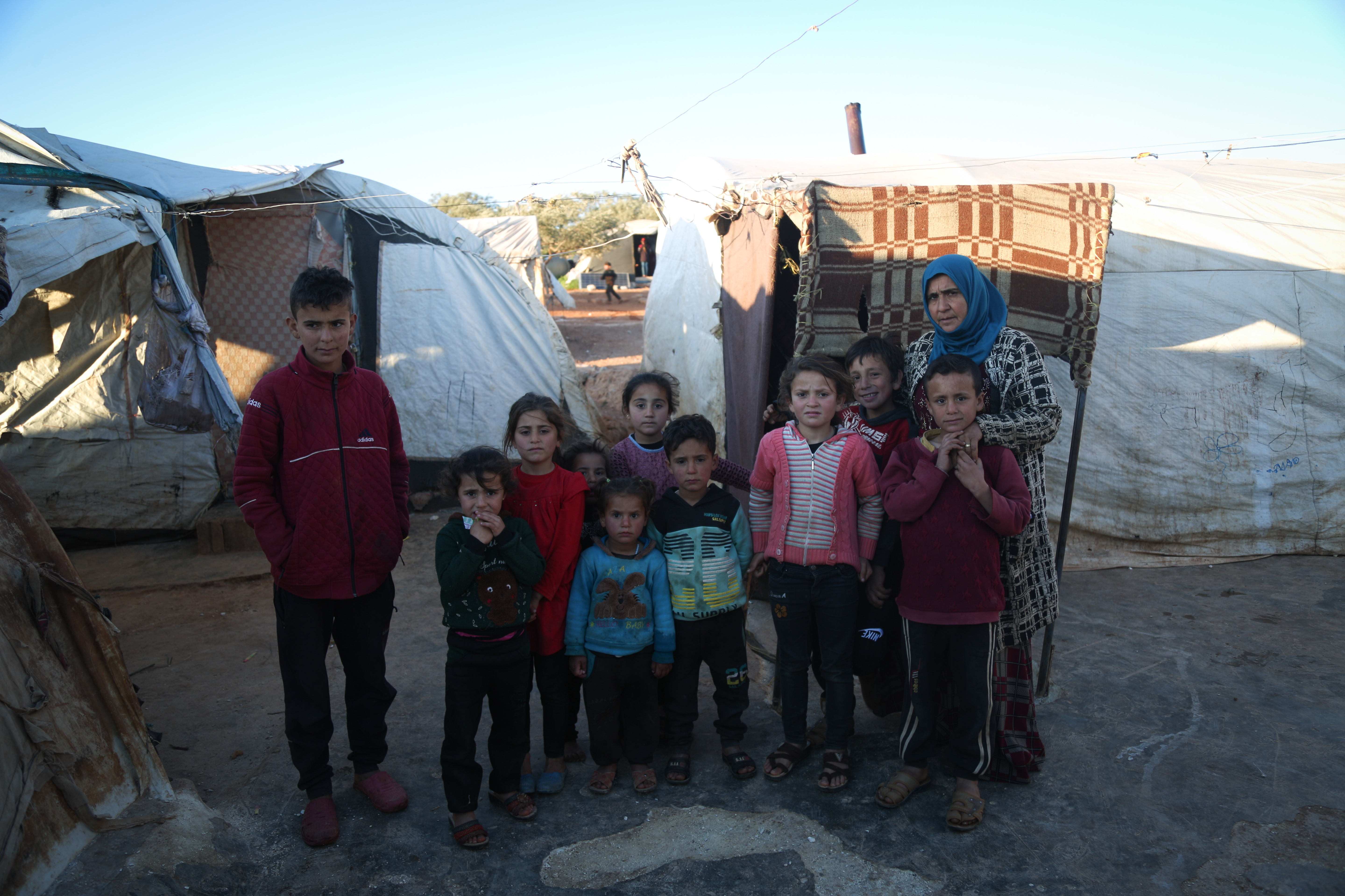 A family stands in the Ahl al-Tah camp for internally displaced people in northwest Syria