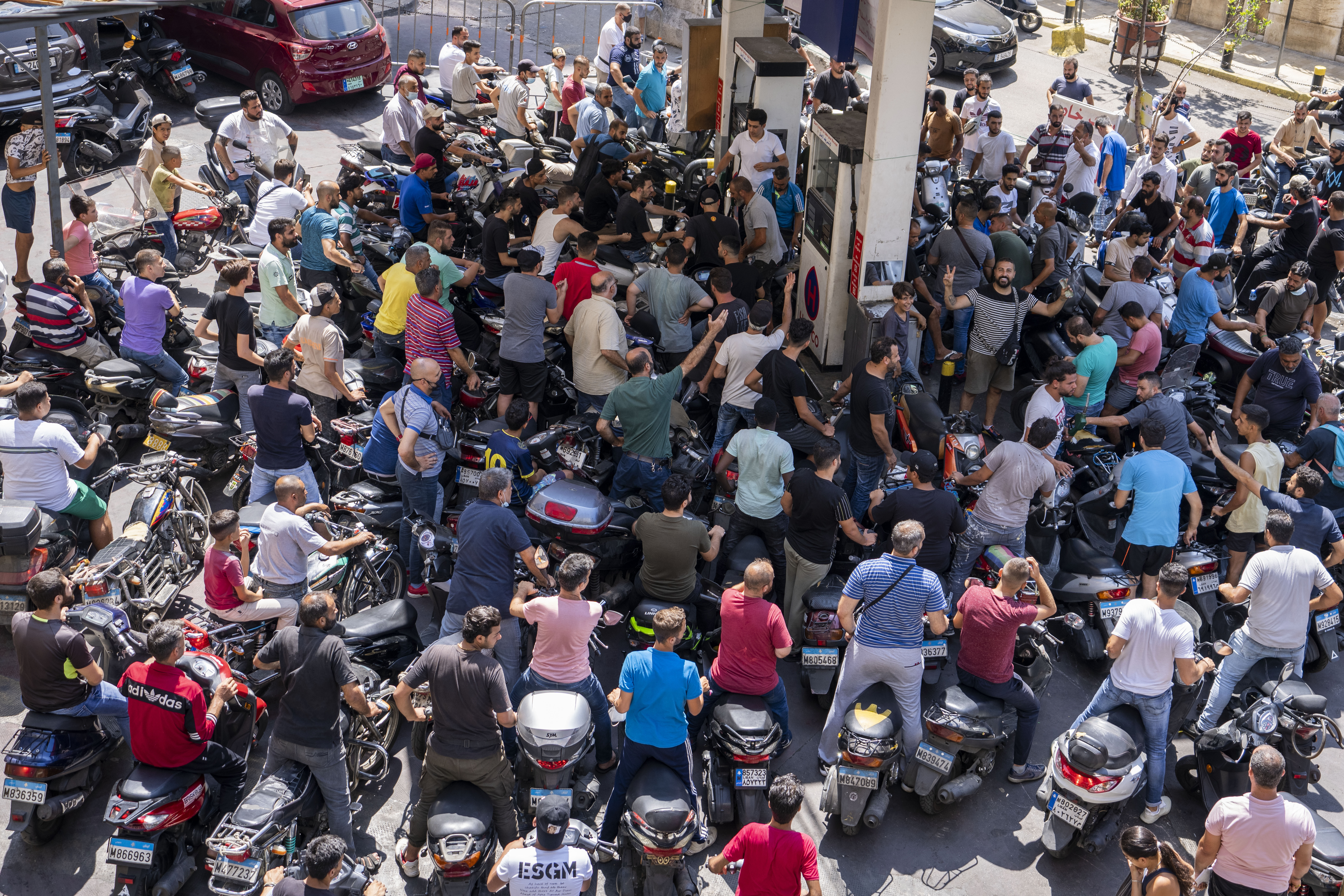 motorcycle drivers wait to get fuel at a gas station