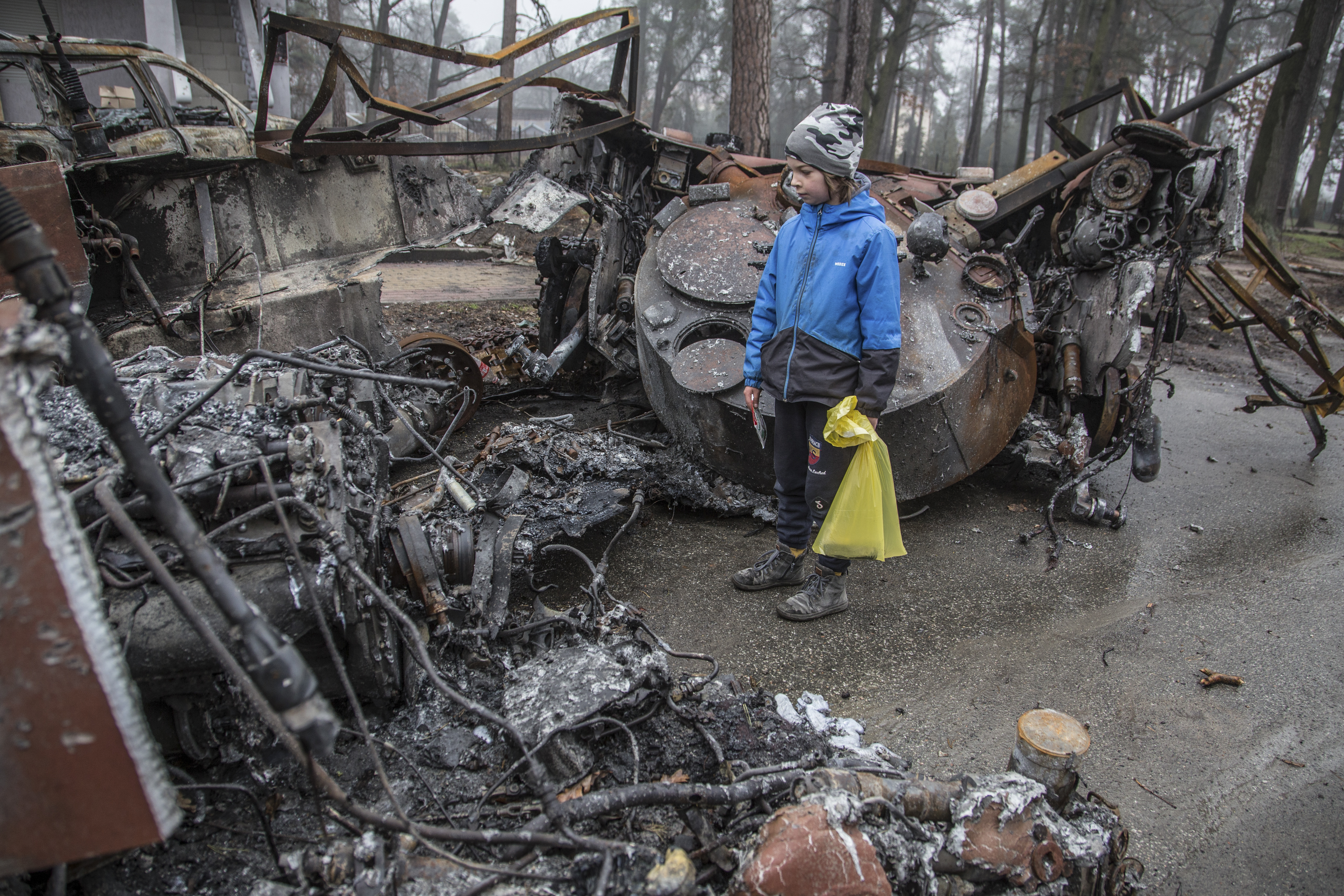 A boy looks at a destroyed Russian tank after recent battles in Bucha, close to Kyiv