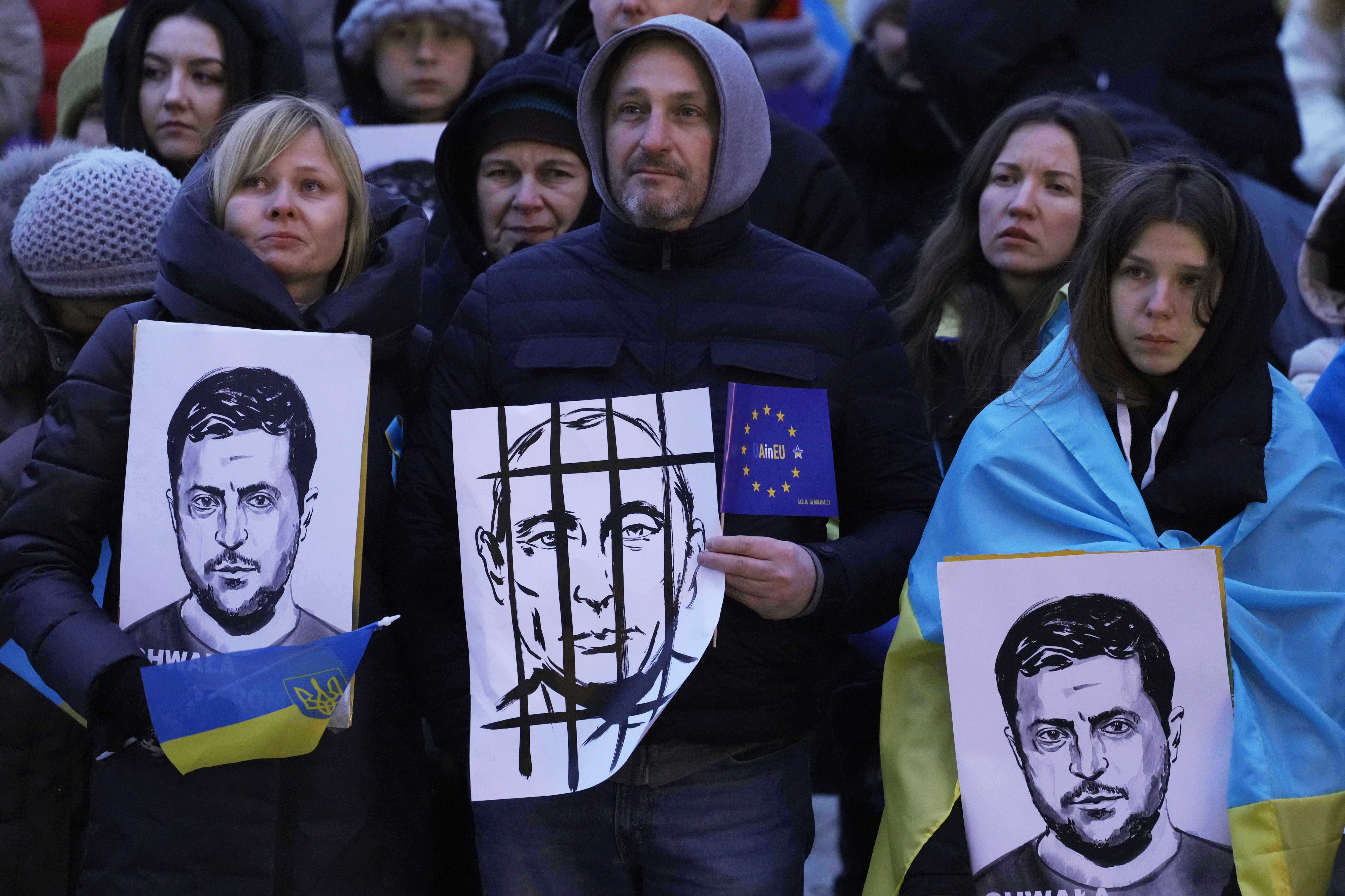 People hold portraits of Ukrainian President Volodymyr Zelenskyy and Russian President Vladimir Putin, centre, during an anti-war rally in front of the Palace of Culture and Science in Warsaw, Poland, on Saturday, April 2, 2022.