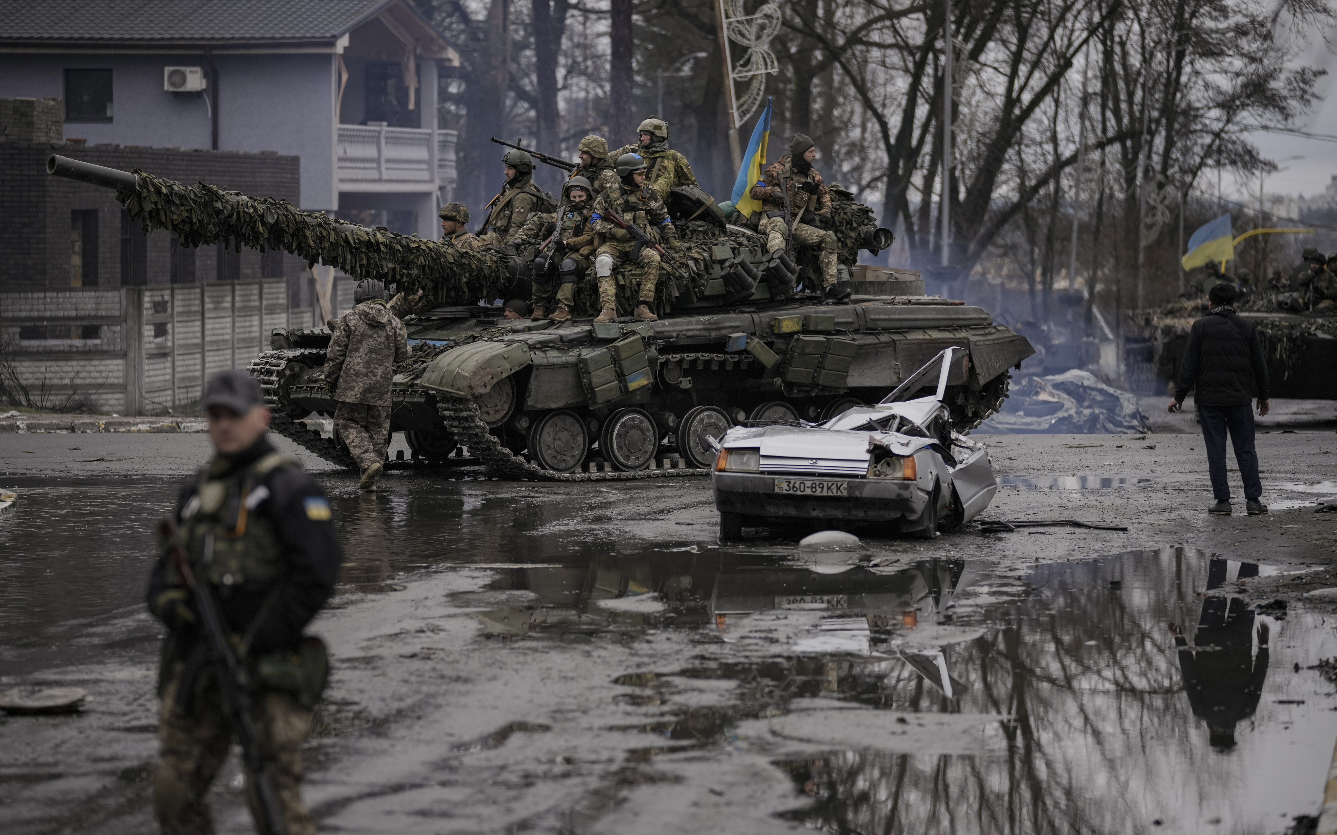 A man stands next to a civilian vehicle that was destroyed during fighting between Ukrainian and Russian forces that still has the driver’s body inside, in a town outside Kyiv