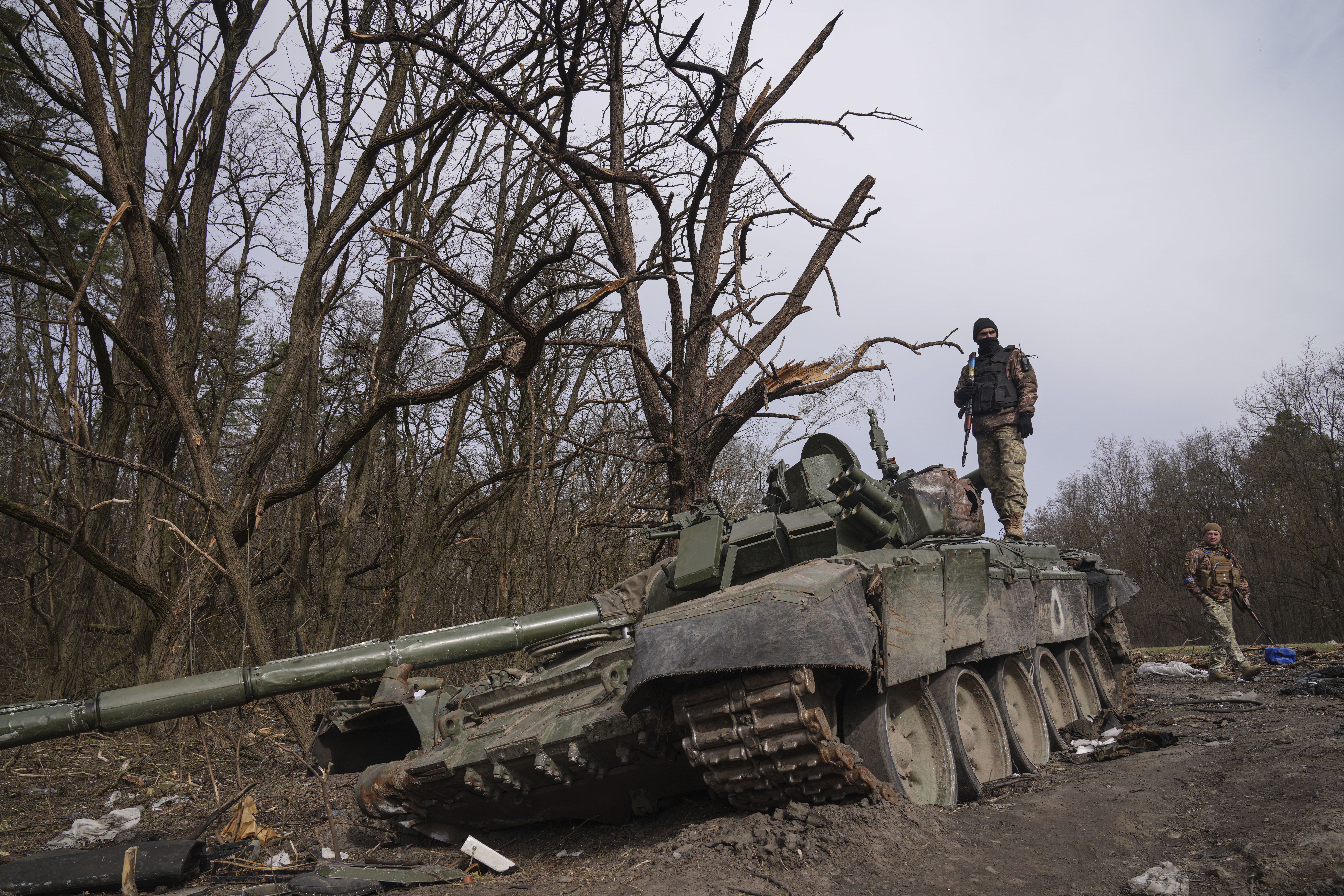 A Ukrainian serviceman stands on top of a destroyed Russian tank in Ukraine’s Chernihiv region