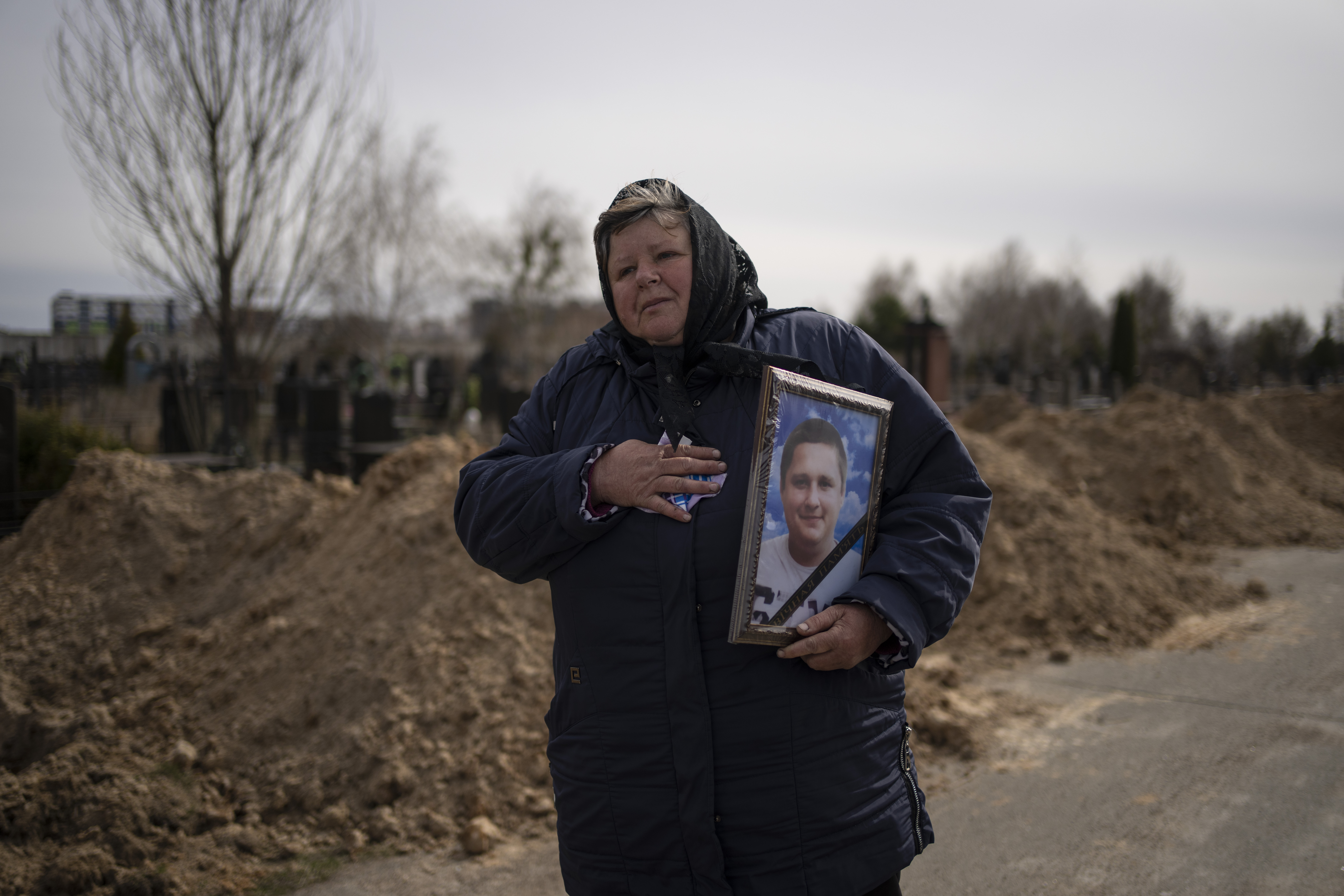A woman carries the portrait of Dmytro Stefienko, 32, a civilian killed during the war with Russia, during his funeral in Bucha, on the outskirts of Kyiv