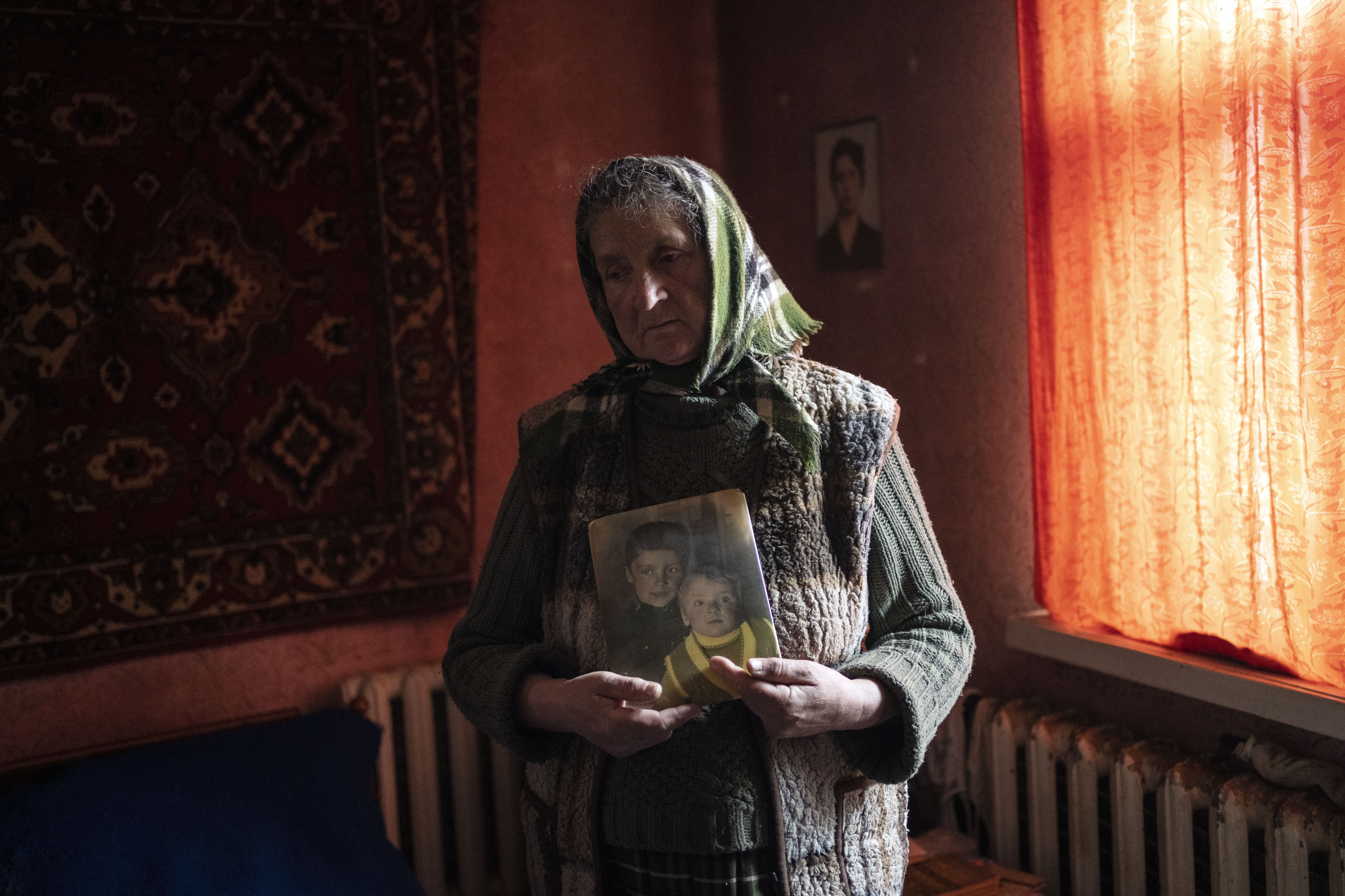 Nadiya Trubchaninova, 70, stands in her bedroom holding a portrait of her sons Oleg Trubchaninov, 46, and Vadym, 48, who was killed by Russian soldiers on March 30 in Bucha, in the outskirts of Kyiv, Ukraine