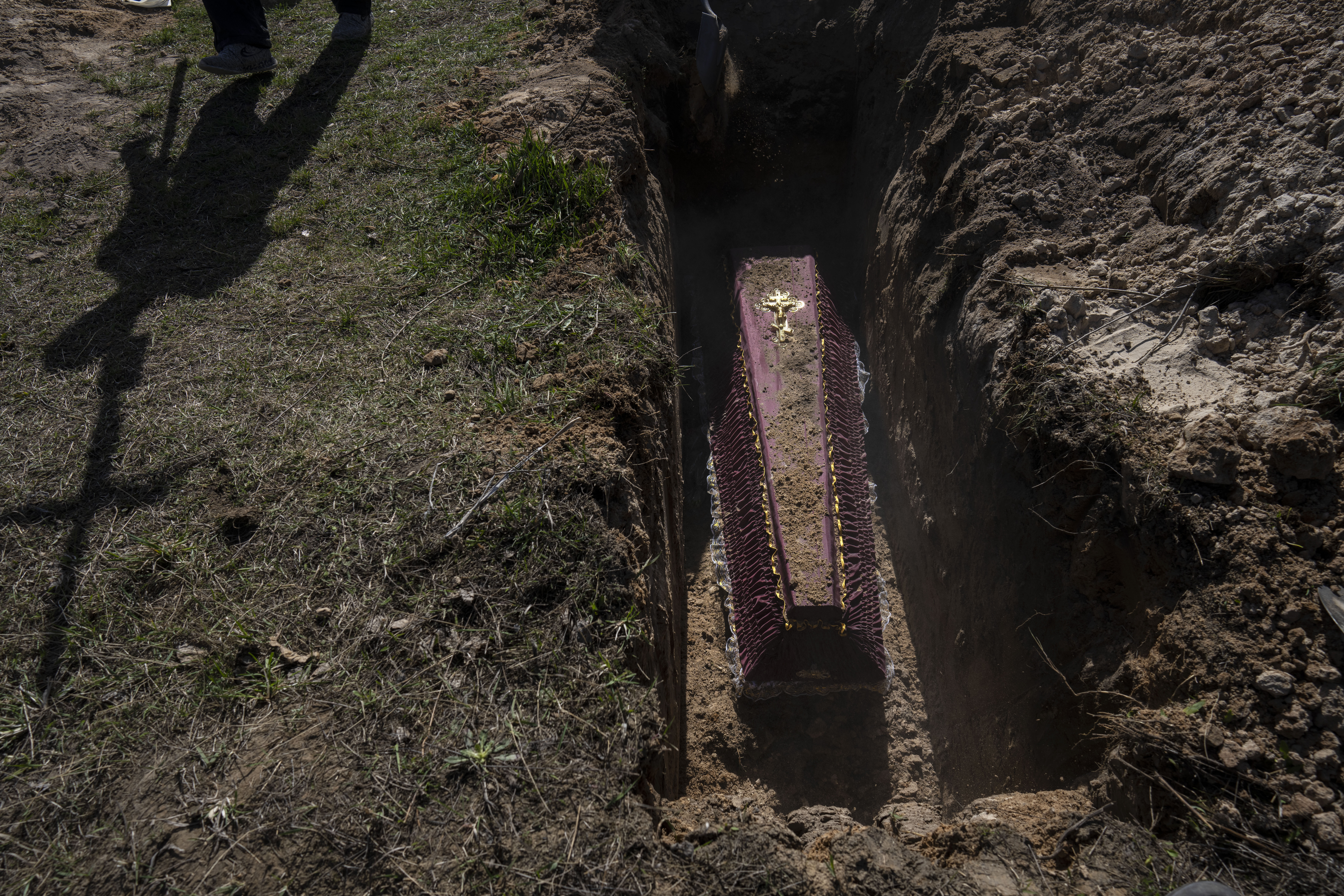 A cemetery worker carries a cross for the tomb of Tetyana Gramushnyak, 75, who was killed by shelling on March 19 while cooking food outside her home in Bucha, on the outskirts of Kyiv, Ukraine