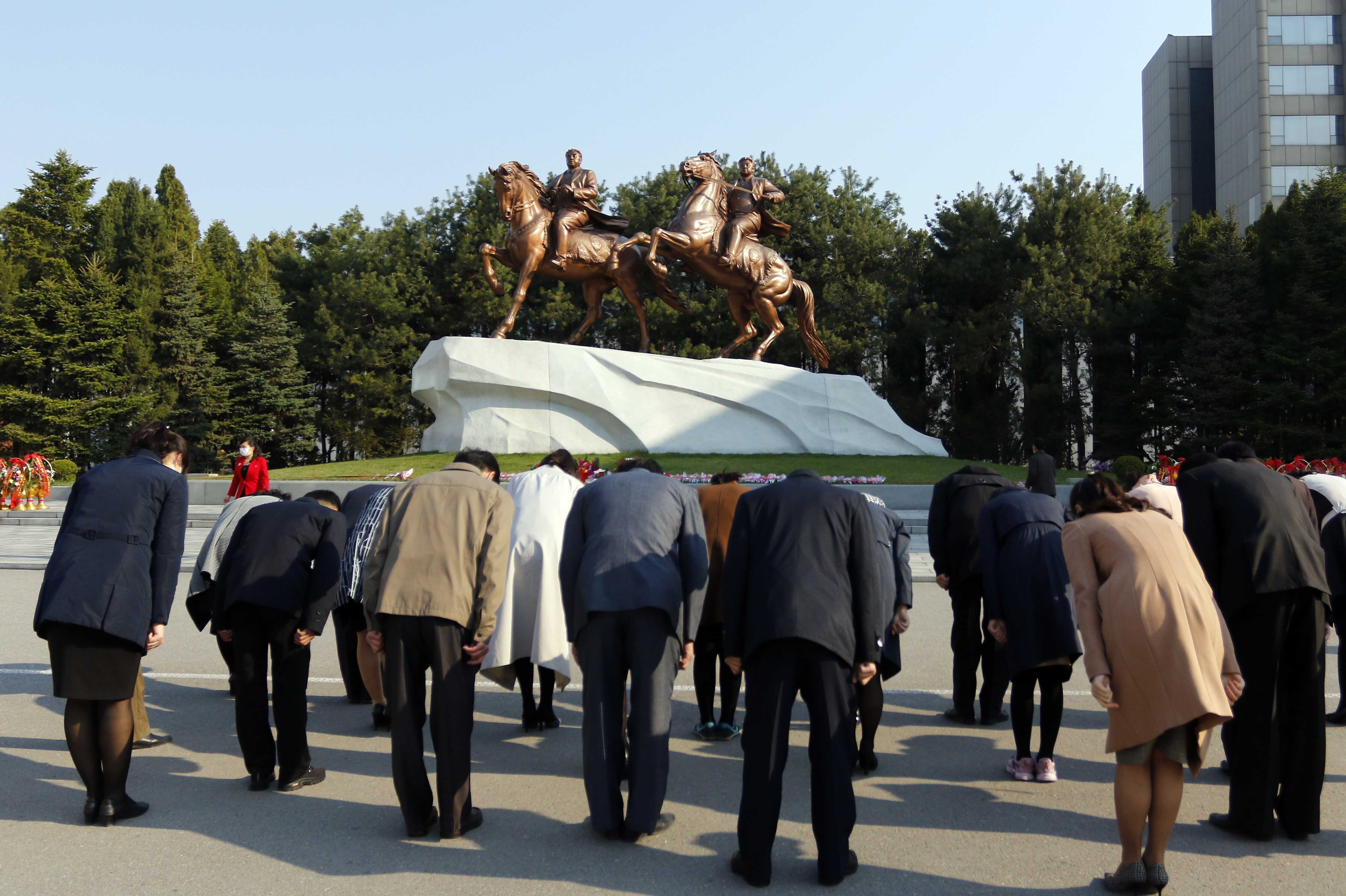 People bow before the statues of late North Korean leaders, Kim Il Sung and Kim Jong Il, during the Day of the Sun celebration on Friday