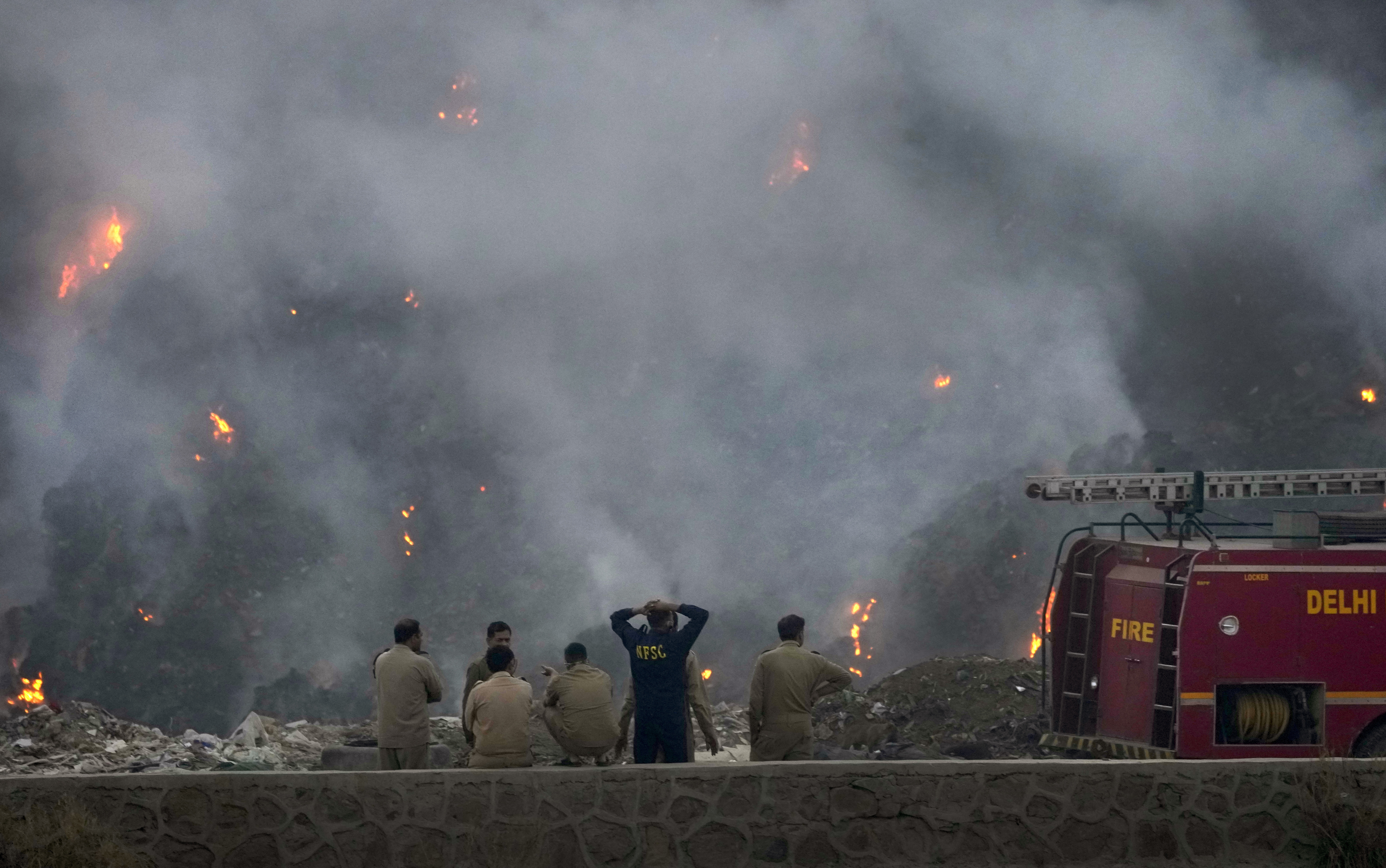Fire officials assess a raging fire at the Bhalswa landfill in New Delhi