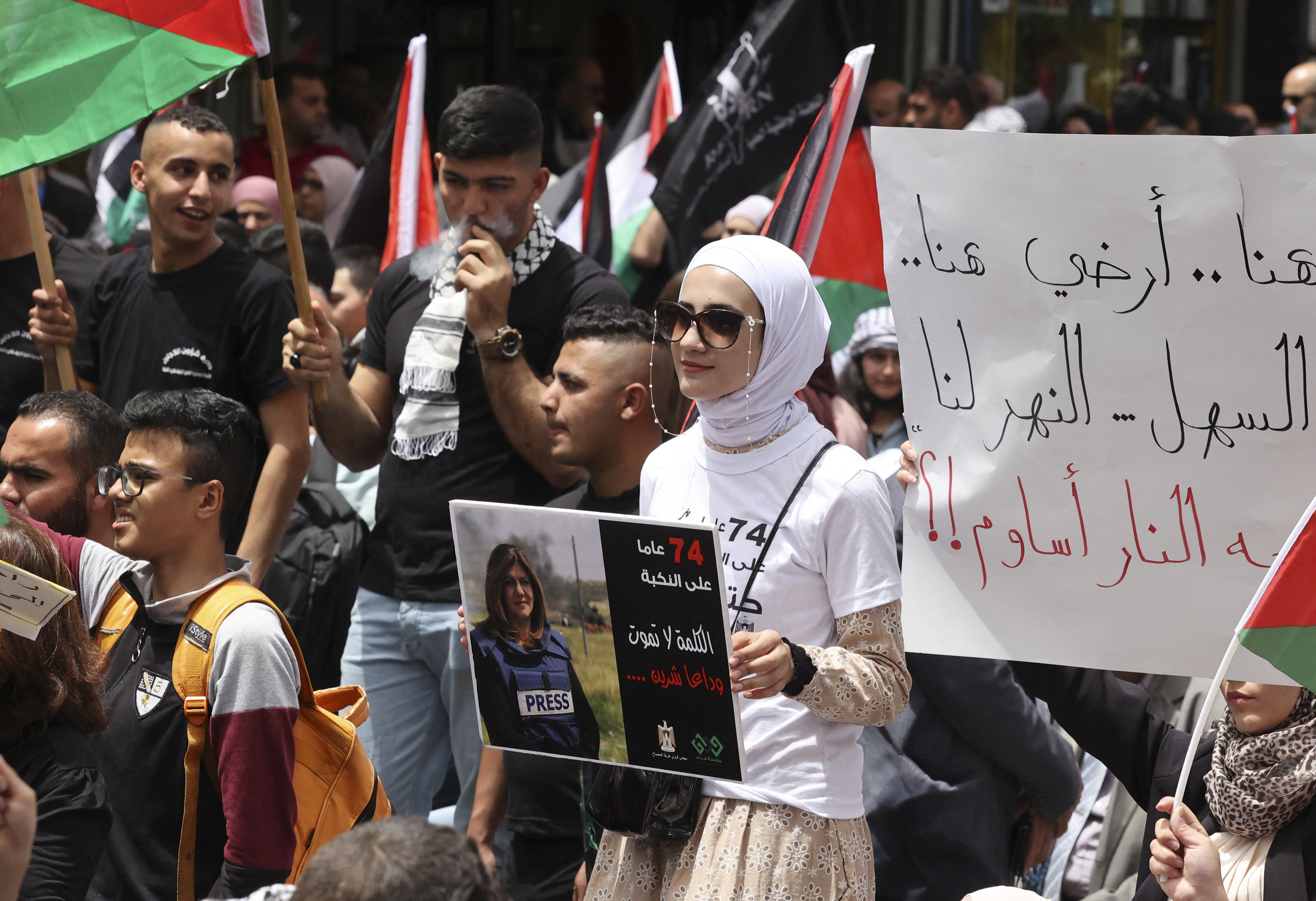 A Palestinian woman holds a poster of slain Al Jazeera journalist Shireen Abu Akleh during a rally to mark the 74th anniversary of the Nakba or ‘catastrophe’, in the occupied West Bank town of Ramallah on May 15, 2022