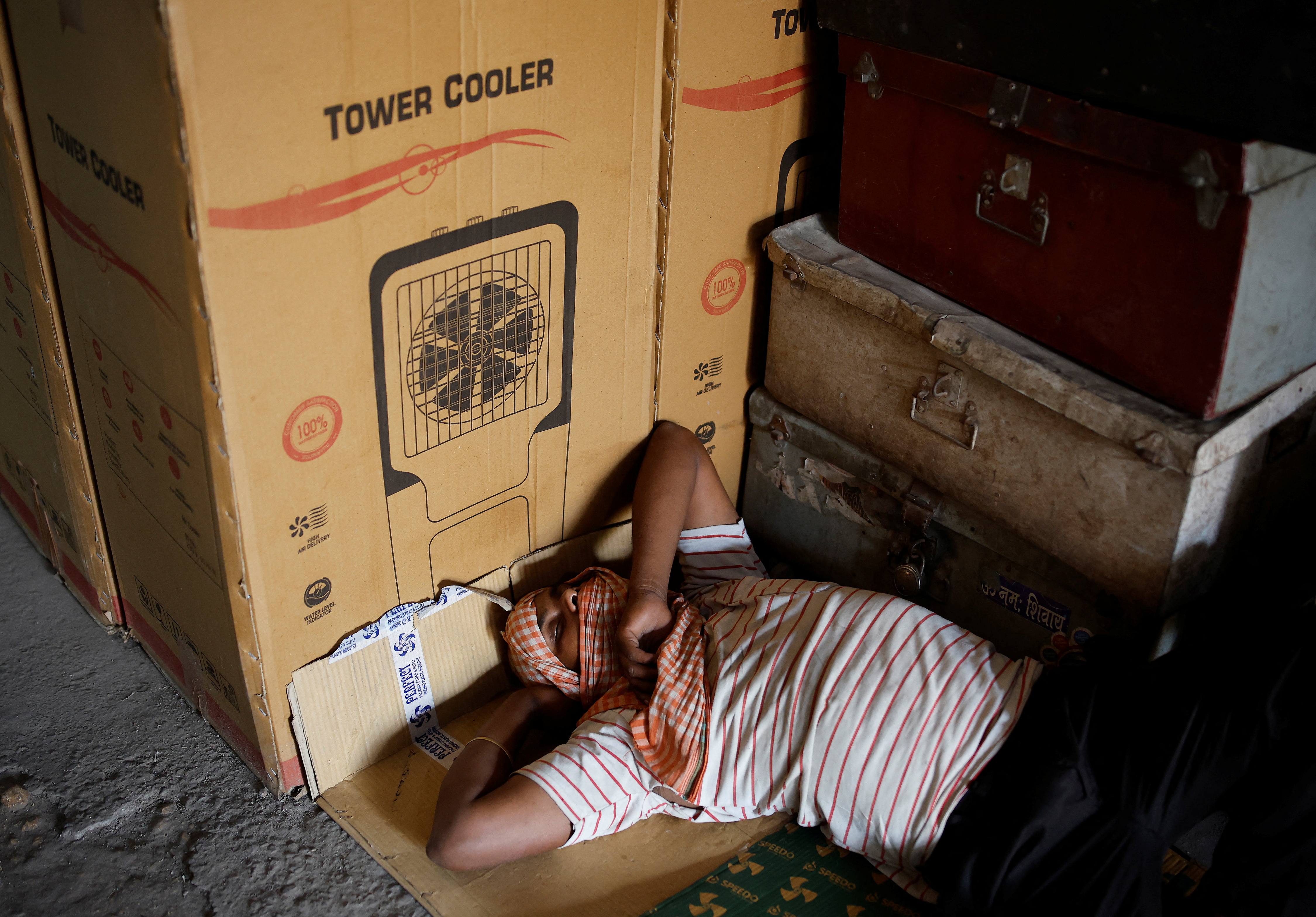 A labourer sleeps at an air cooler market on a hot summer day in New Delhi