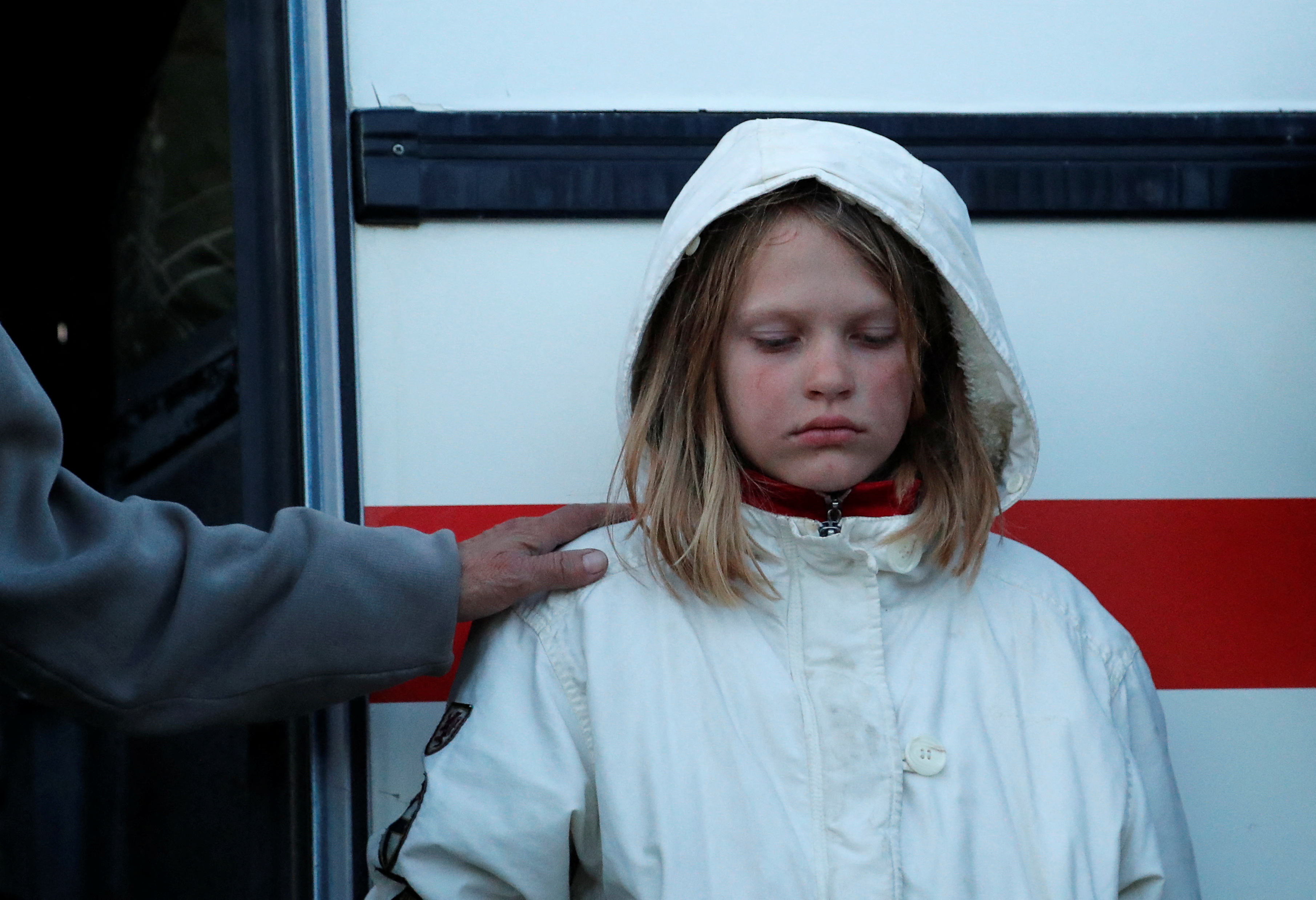 A girl, who was evacuated from Mariupol in the course of Ukraine-Russia conflict, stands outside a bus near a temporary accommodation centre in the village of Bezimenne in the Donetsk region, 